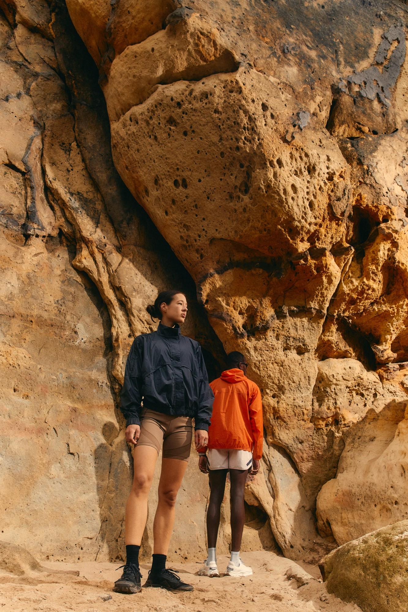 Two figures standing under a sandstone overhang
