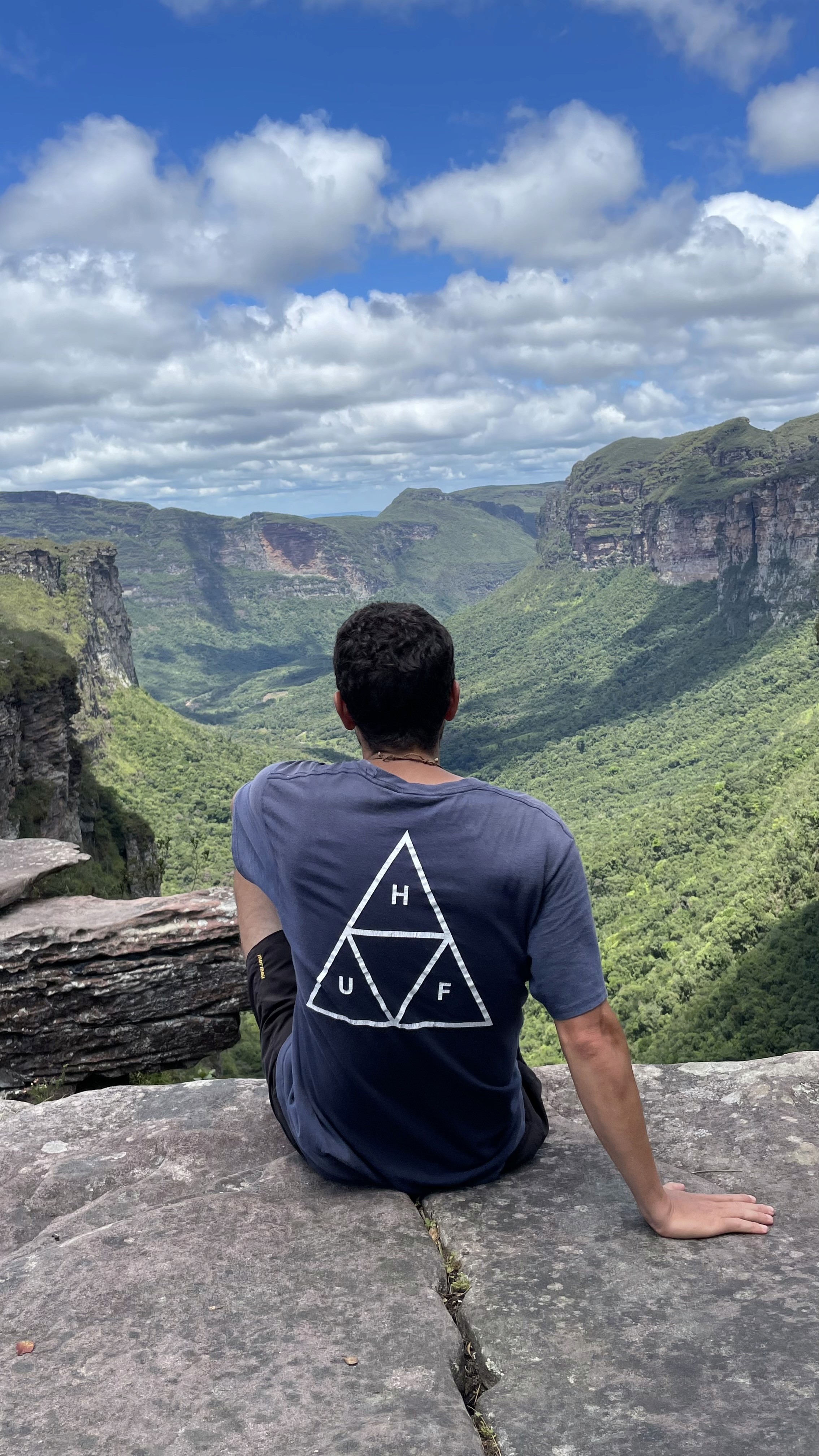 Me sitting on a cliff edge overseeing a forest in a valley in Brazil