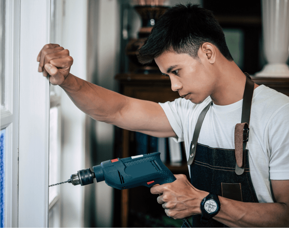 A technician in a white shirt using a power drill on a door, emphasizing comprehensive door repair services.