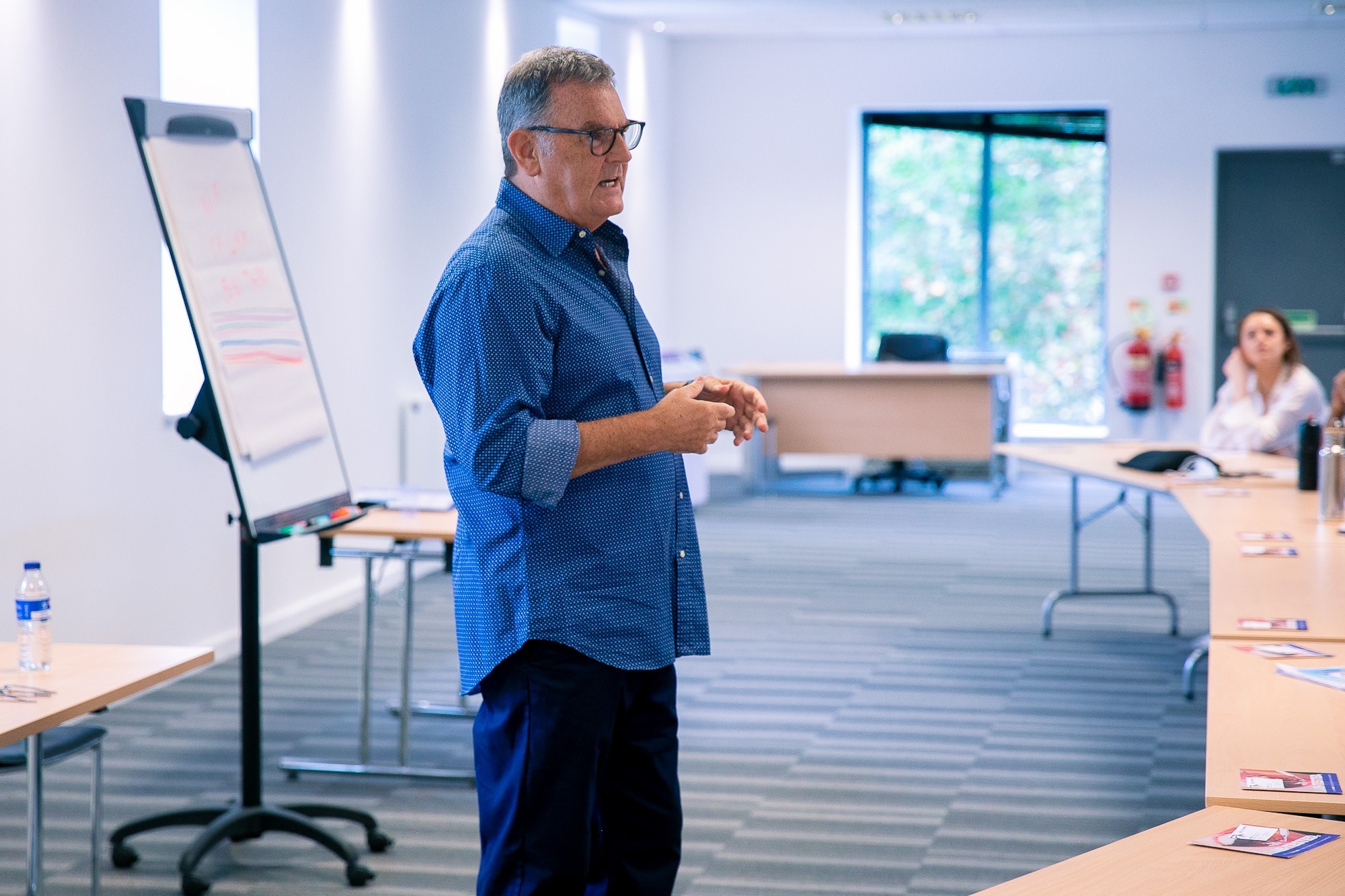 Three professionals in a modern office hallway engaged in a discussion, showcasing a collaborative and professional atmosphere.