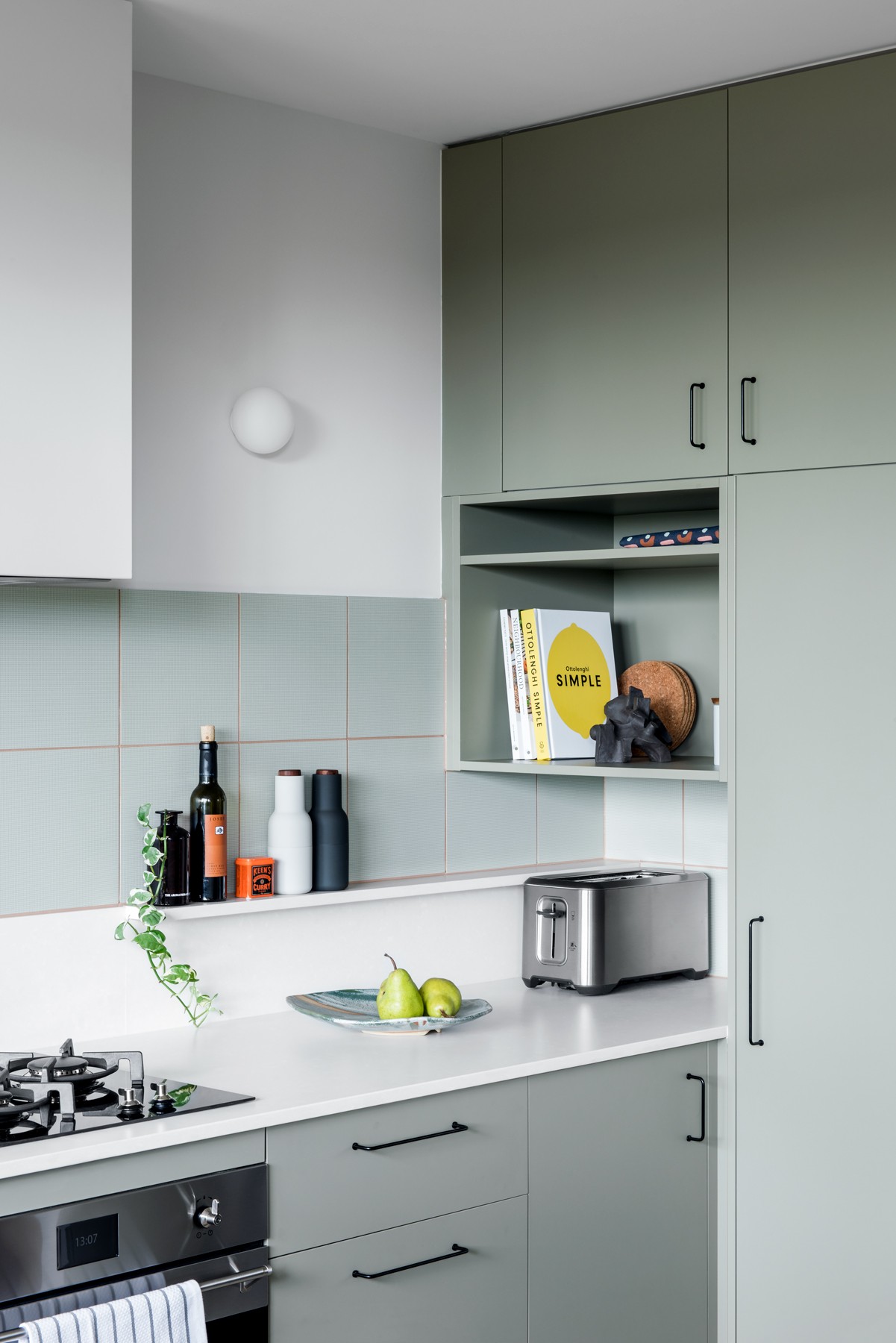 Kitchen joinery and shelving at Glenhaven, combining open display, integrated appliances, and a restrained mid-century influenced palette.