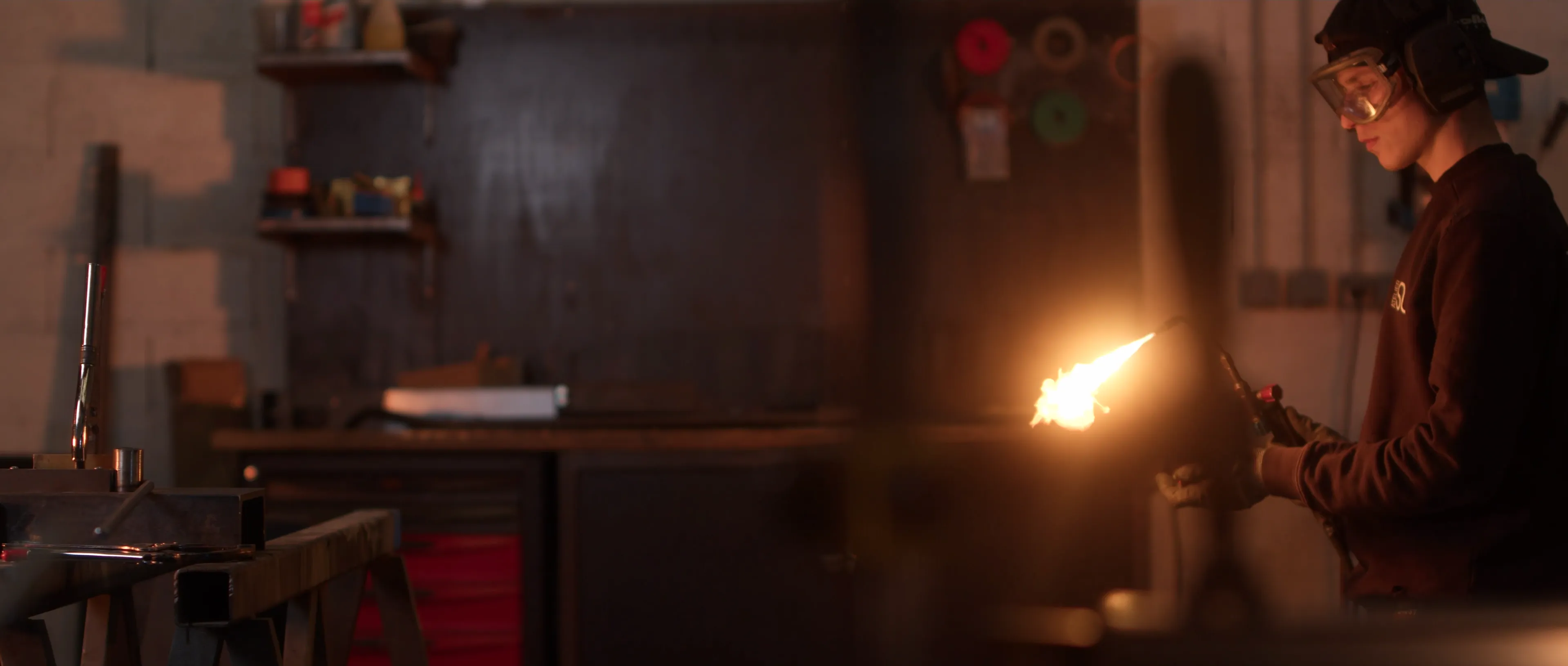 Jeune artisan utilisant un chalumeau dans un atelier industriel.