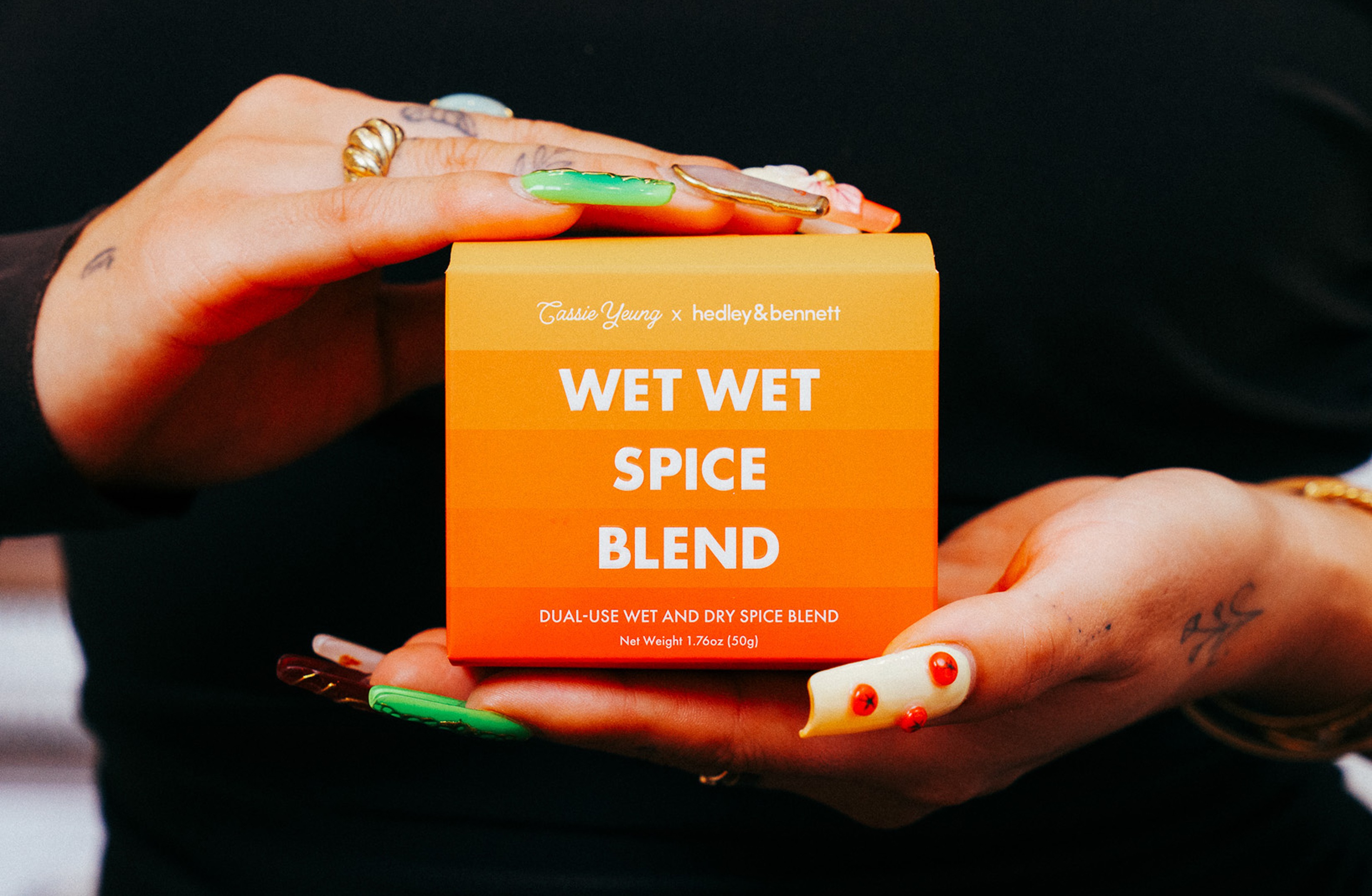 A man in a purple suit uses a PAX vaporizer as he waters the lawn.