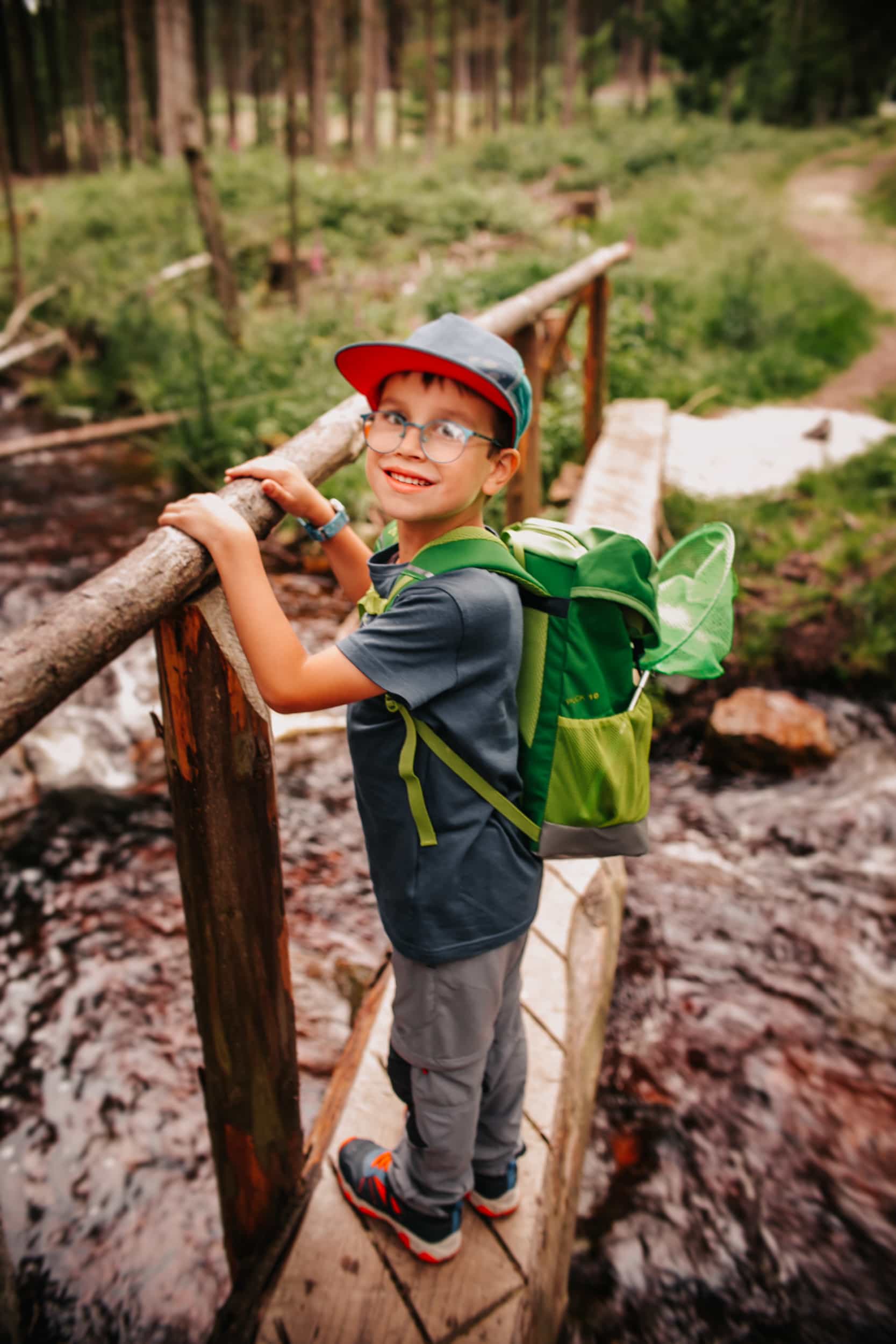 Boy on a pier with a green backpack on his back