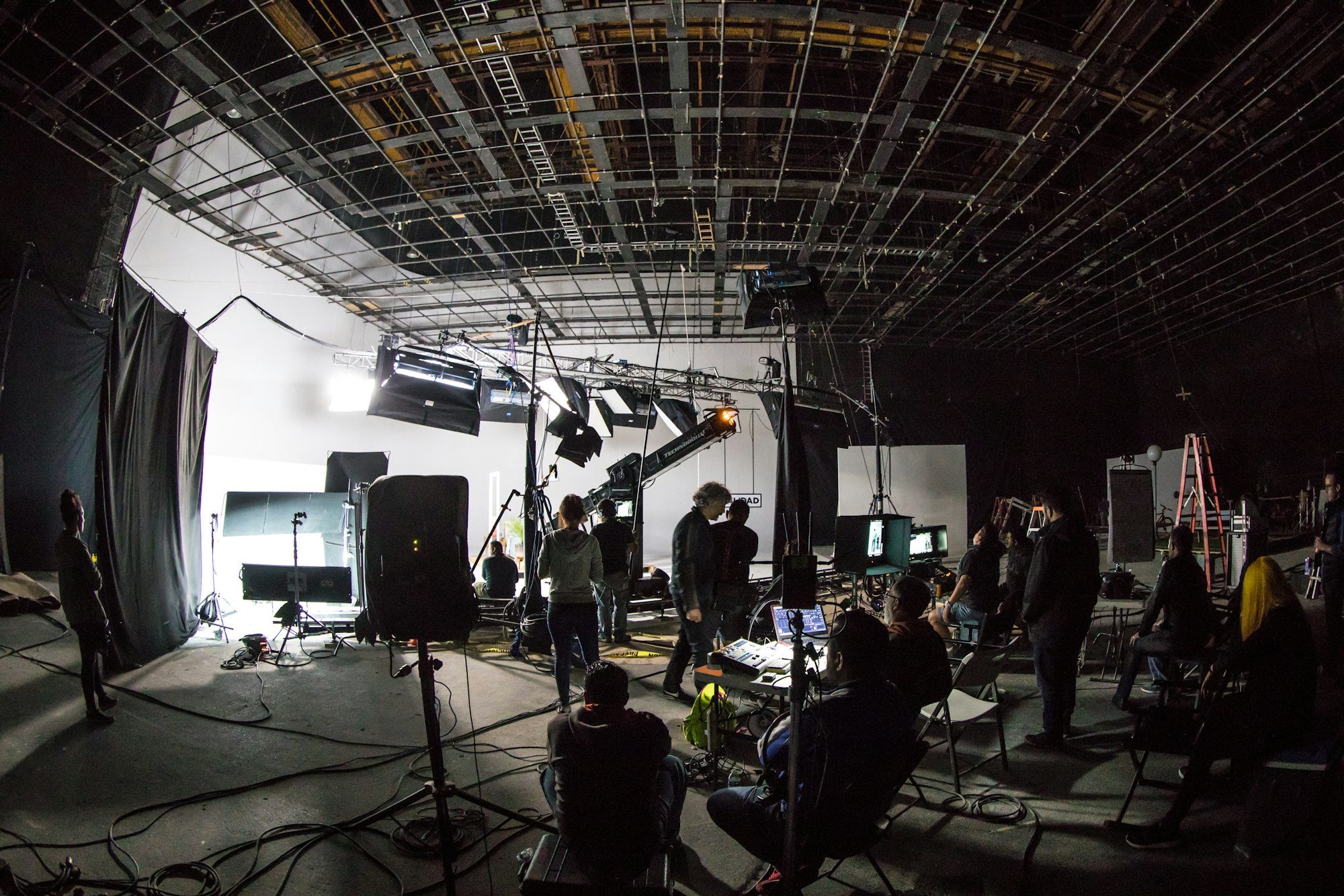 Film crew working on a large production set with lighting rigs and cameras