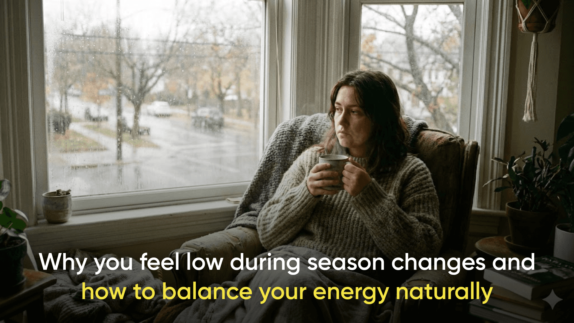 Person sitting by a window on a rainy day holding a warm cup of tea, looking thoughtful, with the text “Why you feel low during season changes and how to balance your energy naturally” displayed on the image.