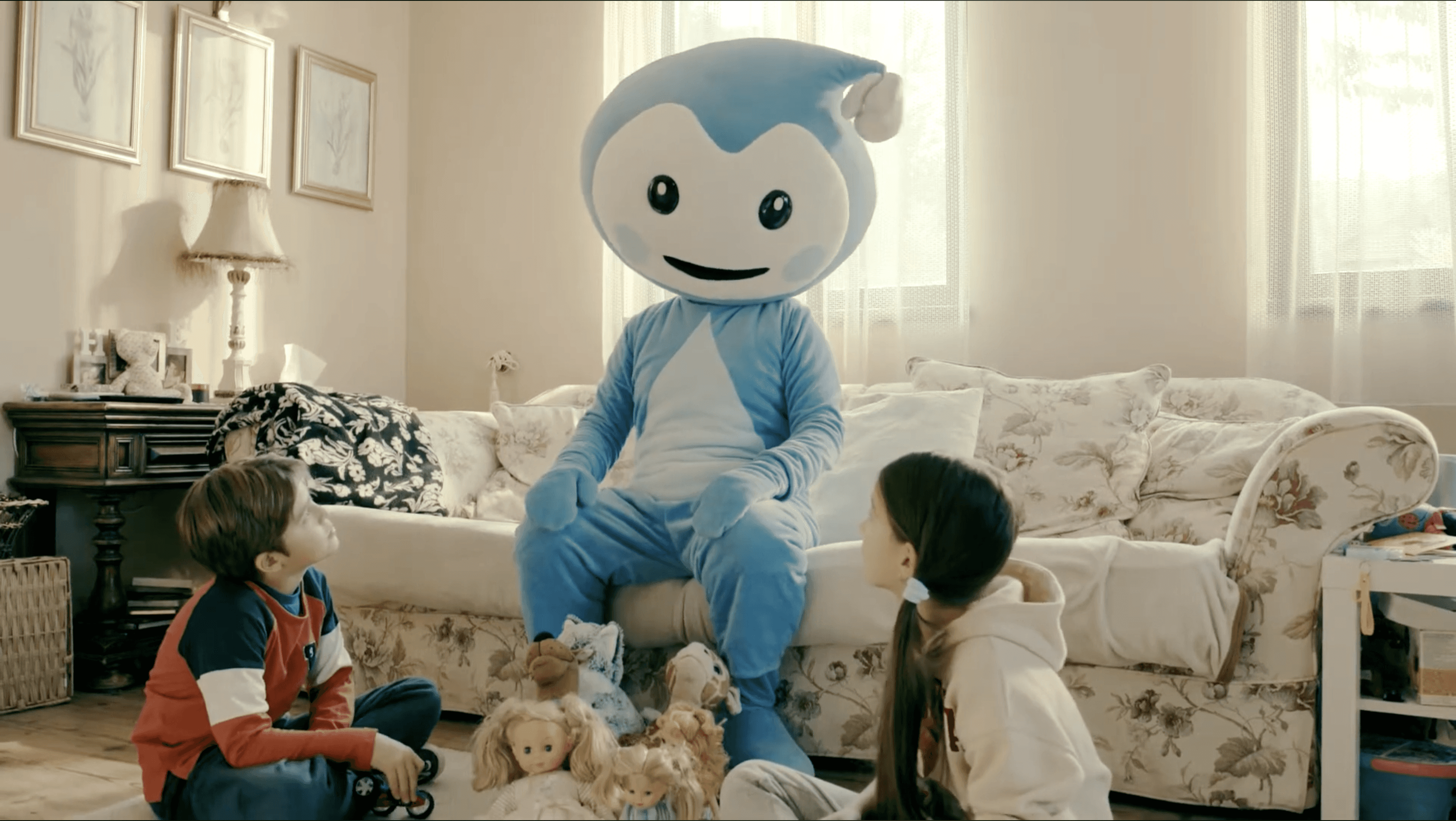 Cseppbarát kékl kabalafigurája tanítja a gyerekeket a kanapén ülve.