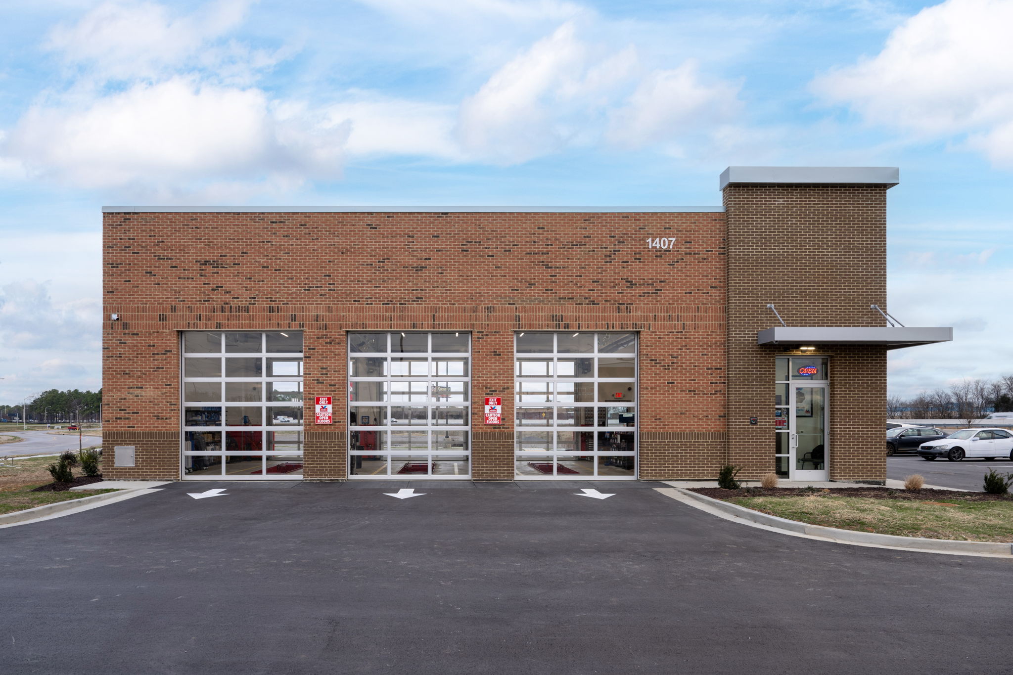 Wide view of a high-end commercial facade featuring grey stacked stone veneer, vertical red architectural slats, and horizontal wood-grain siding installed by Kith Exteriors.