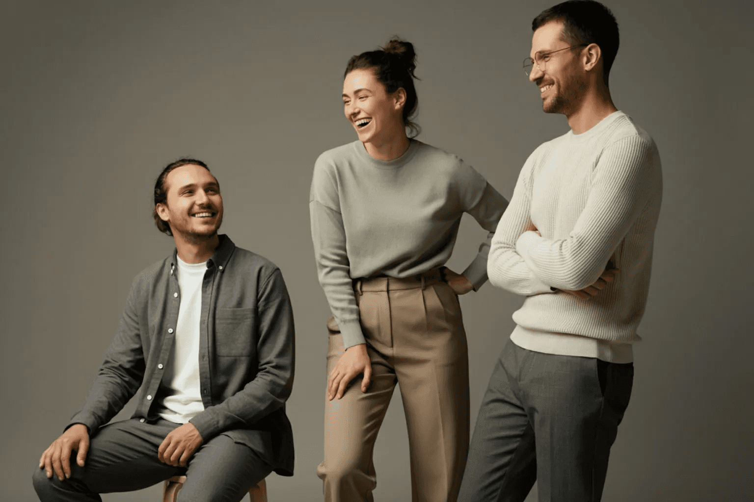 Three colleagues smiling and chatting together in a studio setting.