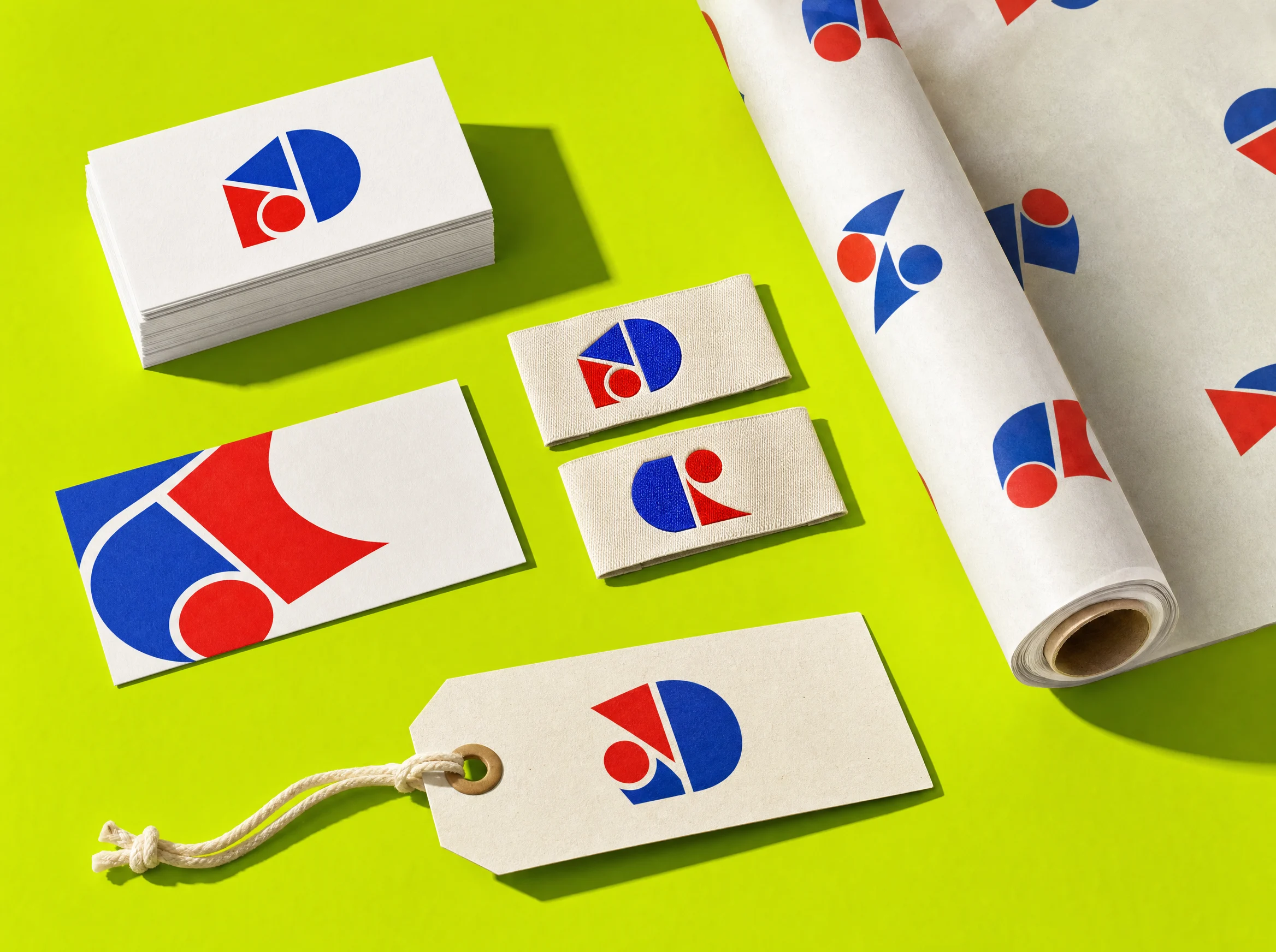Business cards, tags and wrapping paper printed with red and blue geometric marks on lime