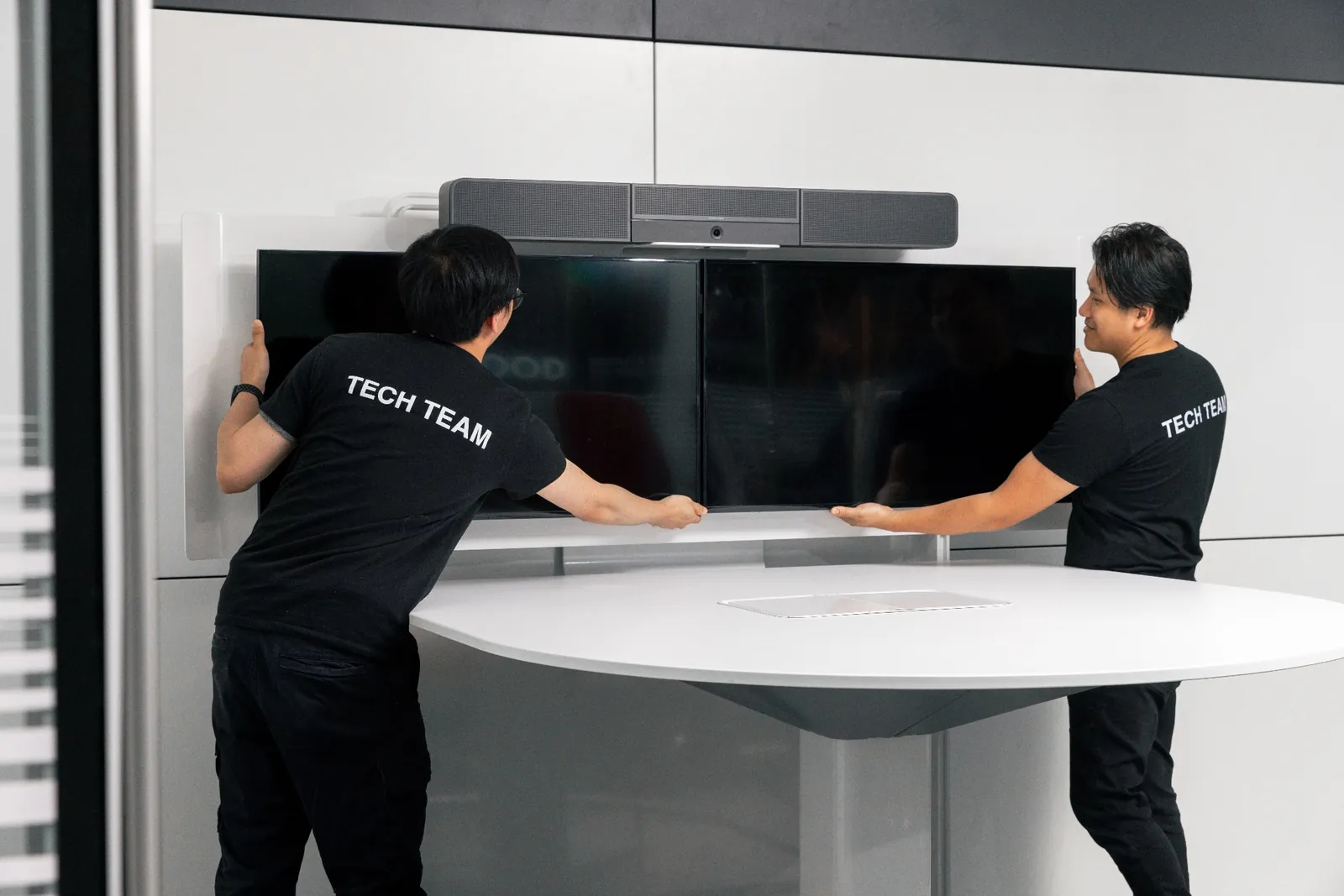 Audio-video technicians installing conference room display and AV equipment in a modern office setup