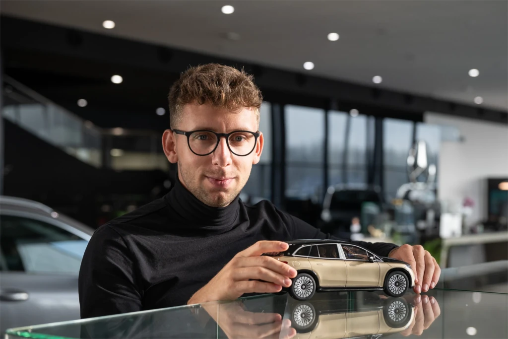 Portret mężczyzny przy blacie na ktorym stoją zabawkowe samochody