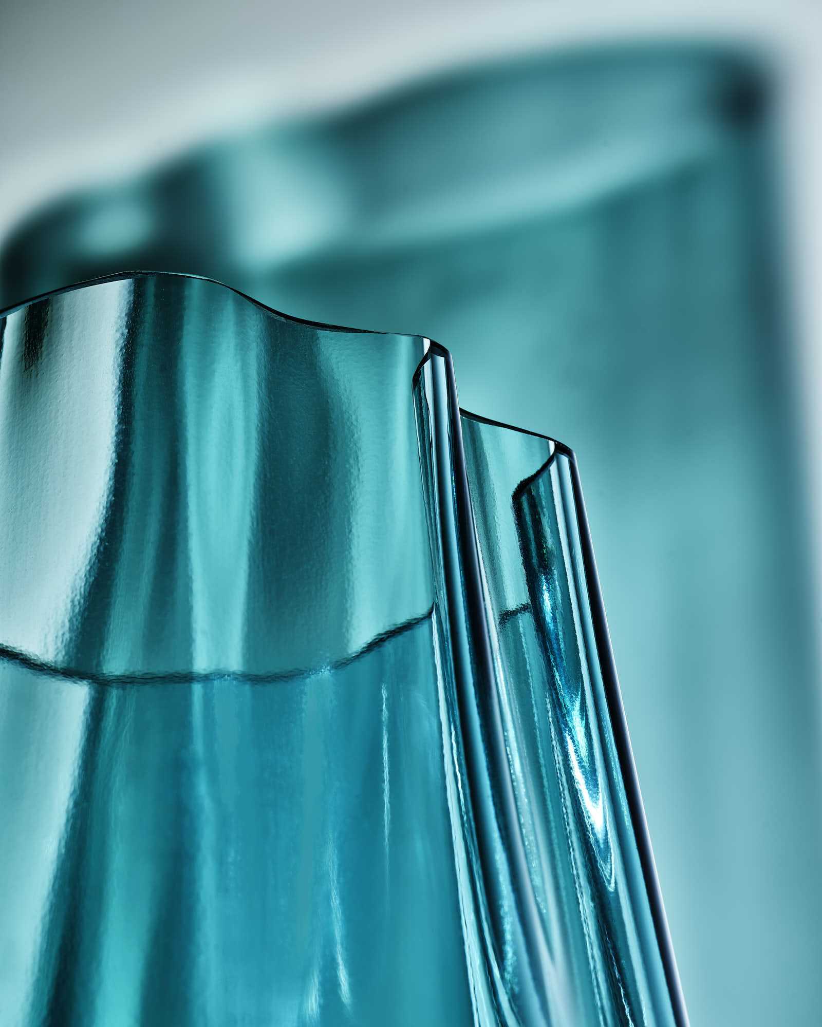 Abstract blue glass sculpture with flowing curves and reflections.