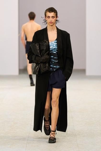 Image may contain Clothing Coat Jacket Blazer Fashion Formal Wear Suit Long Sleeve Sleeve Adult Person and Shorts