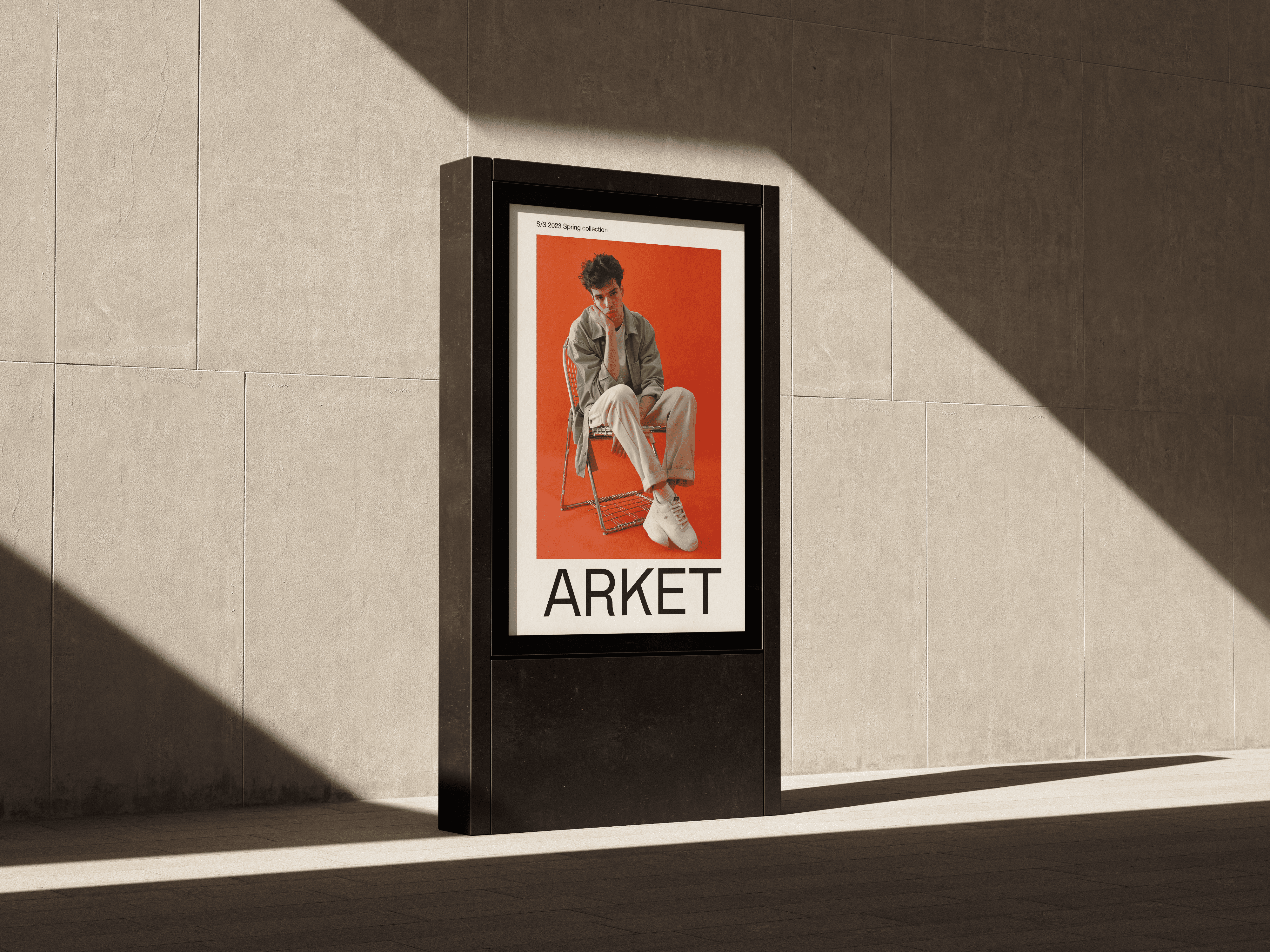 Arket outdoor campaign poster featuring bold typography and warm-toned fashion photography displayed on a sunlit concrete wall