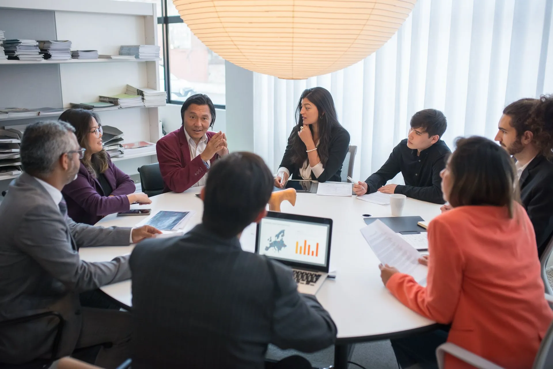 a group of people sitting at a table with laptops