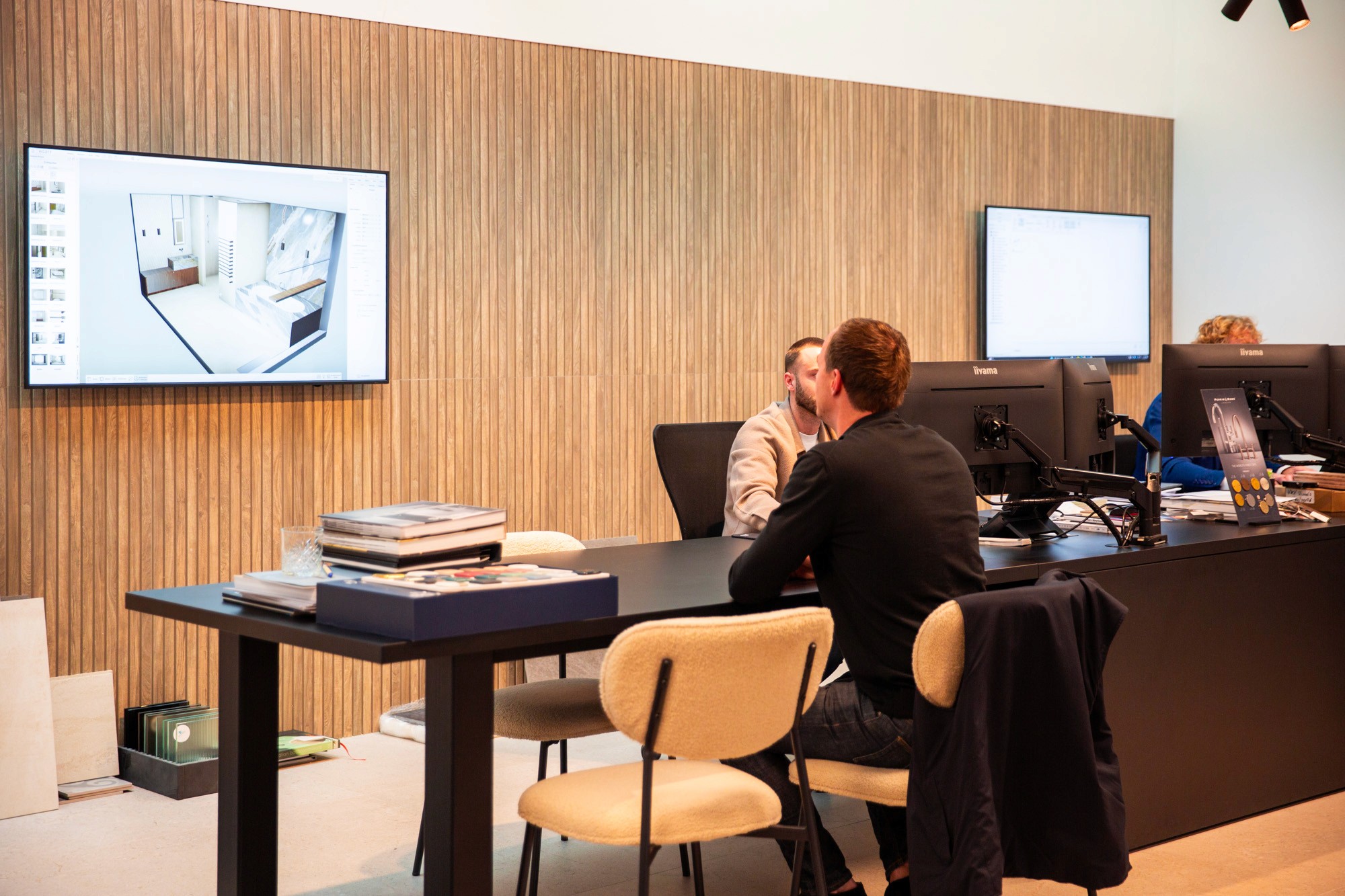 Modern interior space with a blue circular coffee table, flowers in a vase, and books neatly arranged.