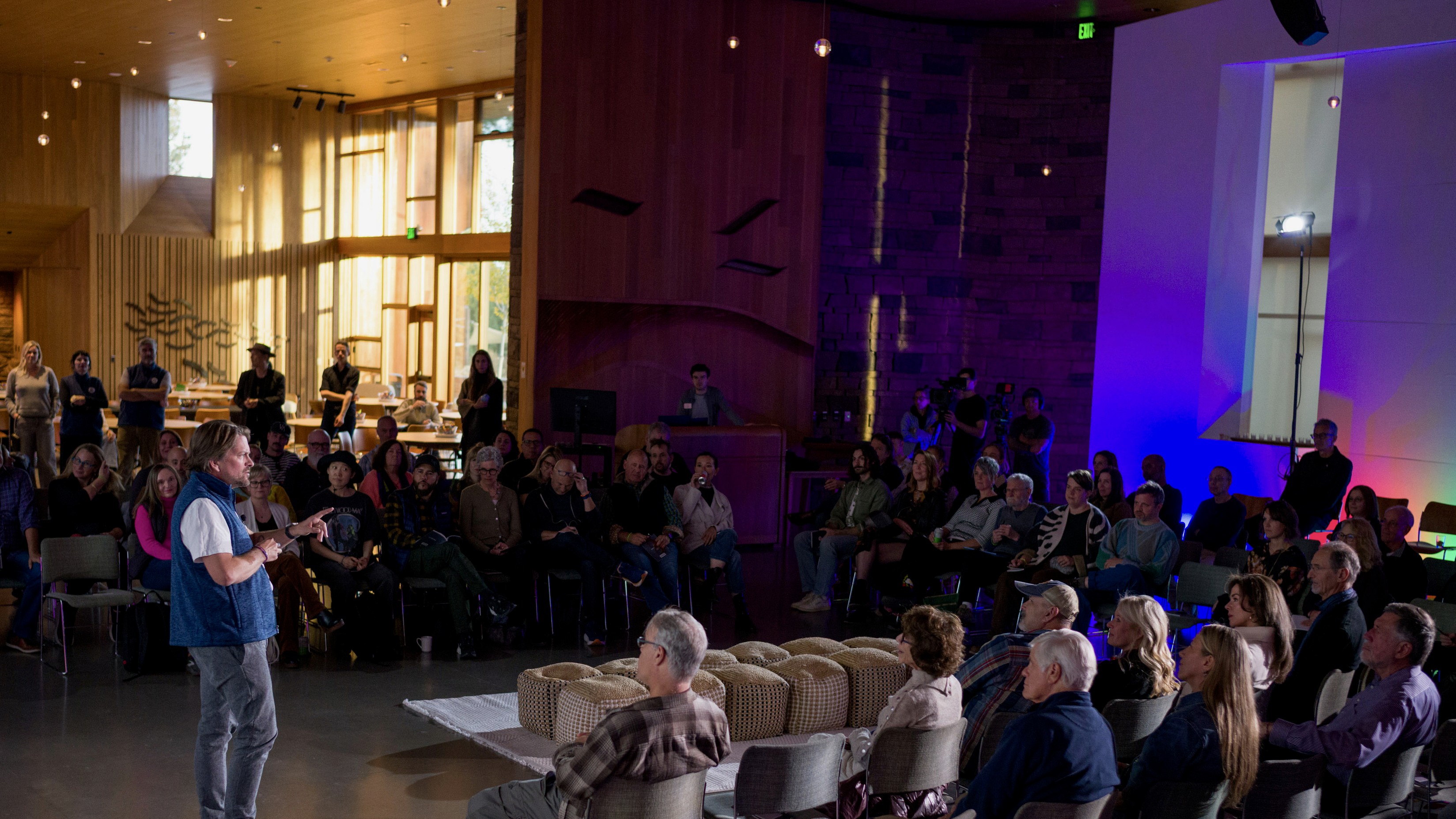 A softly lit hallway with a series of arched doorways, warm-toned walls, and wood flooring leading toward a seating area with neutral furniture.
