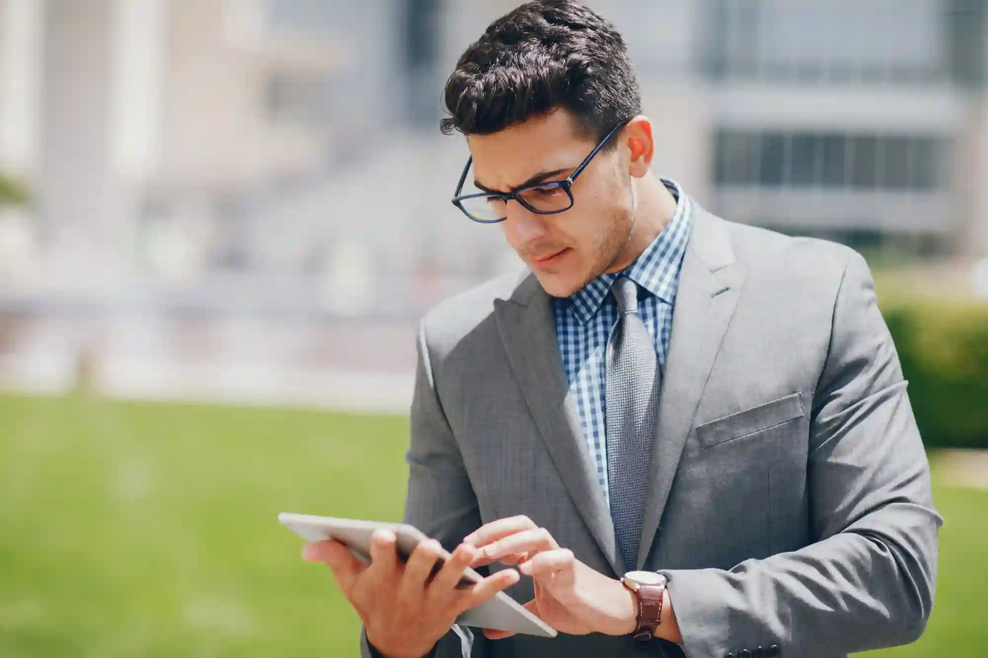 A businessman in a suit uses a tablet outdoors, showcasing the mobility of modern digital real estate tools.