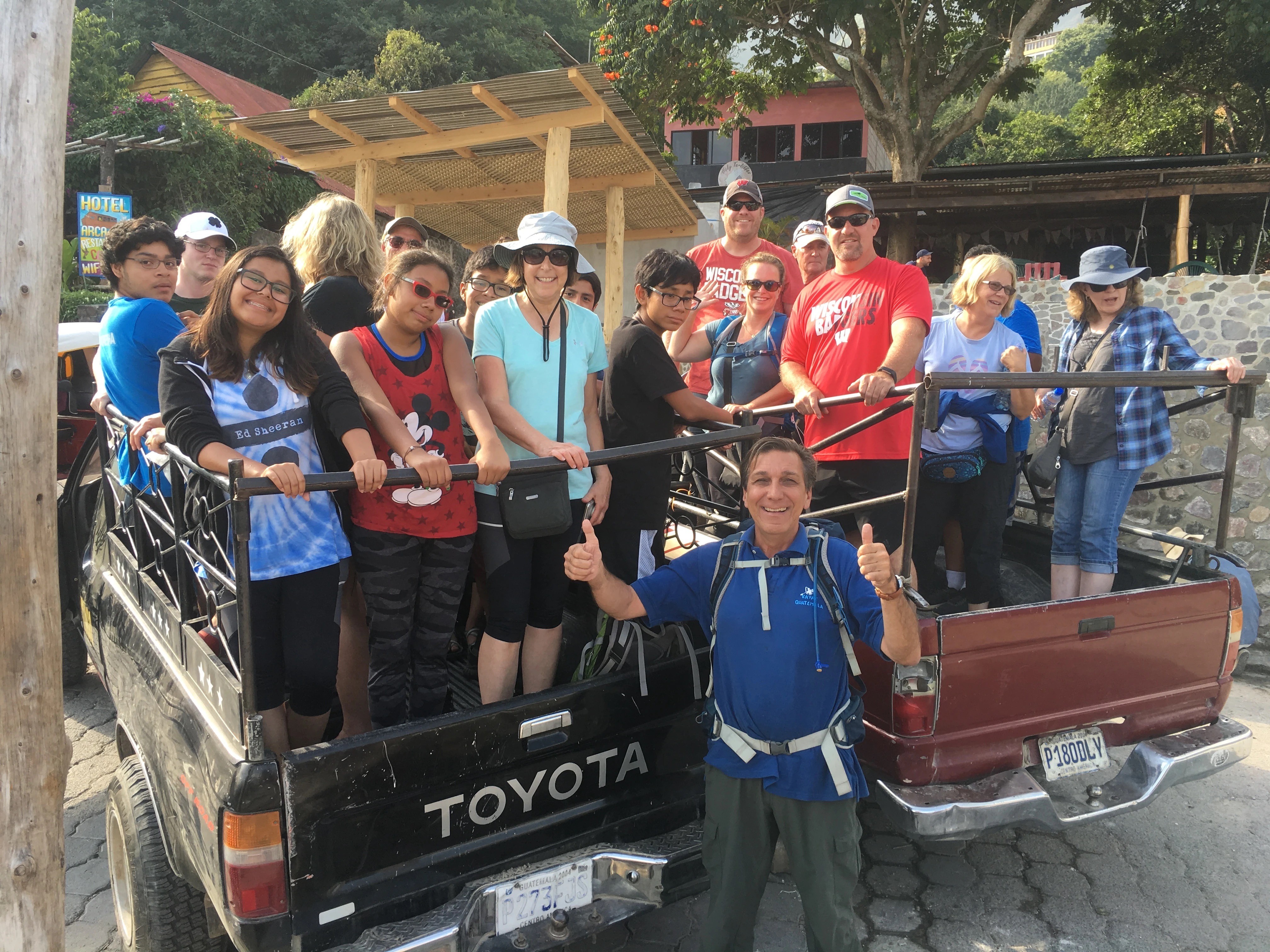 A group of people gathered in the back of a truck, smiling and posing for a photo outdoors.