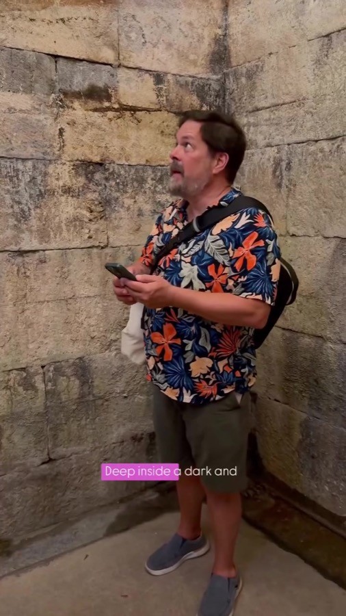 Vineyards & Voyages campaign still: a traveller checking his phone in a narrow stone passageway.
