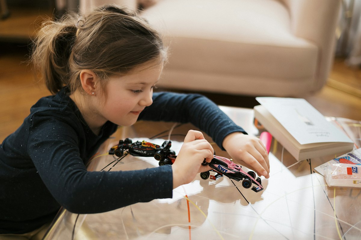 A girl concentrating as she builds a toy car
