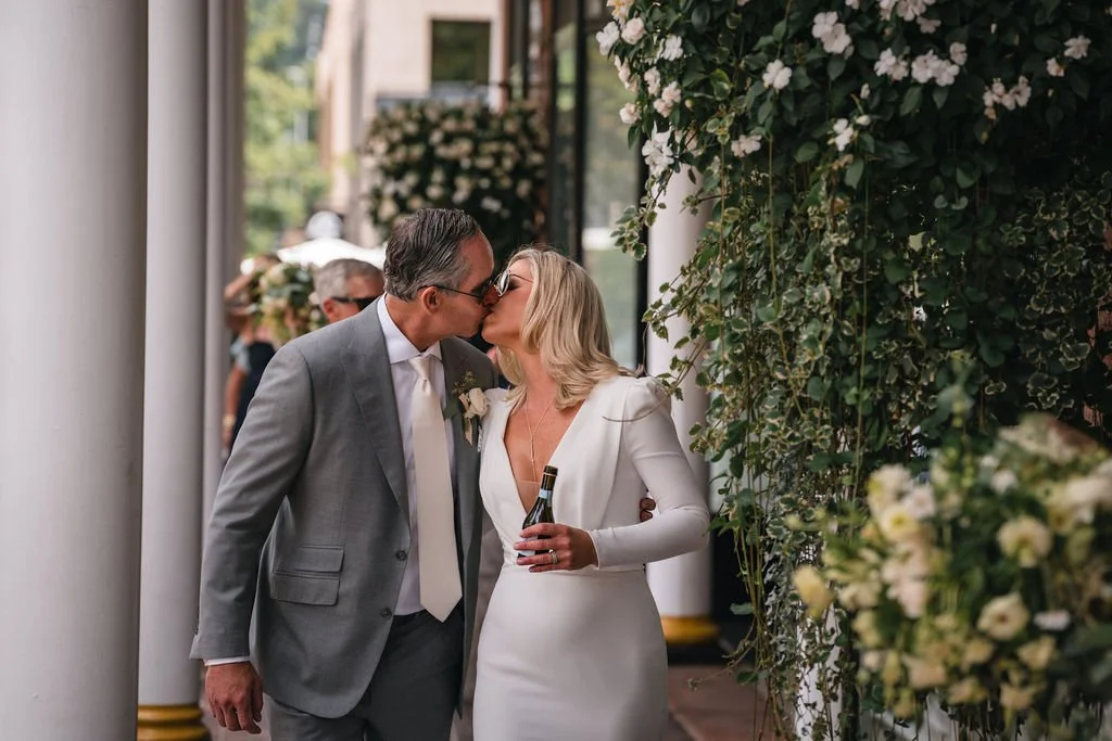 Newlyweds kissing beneath a flower-covered doorway