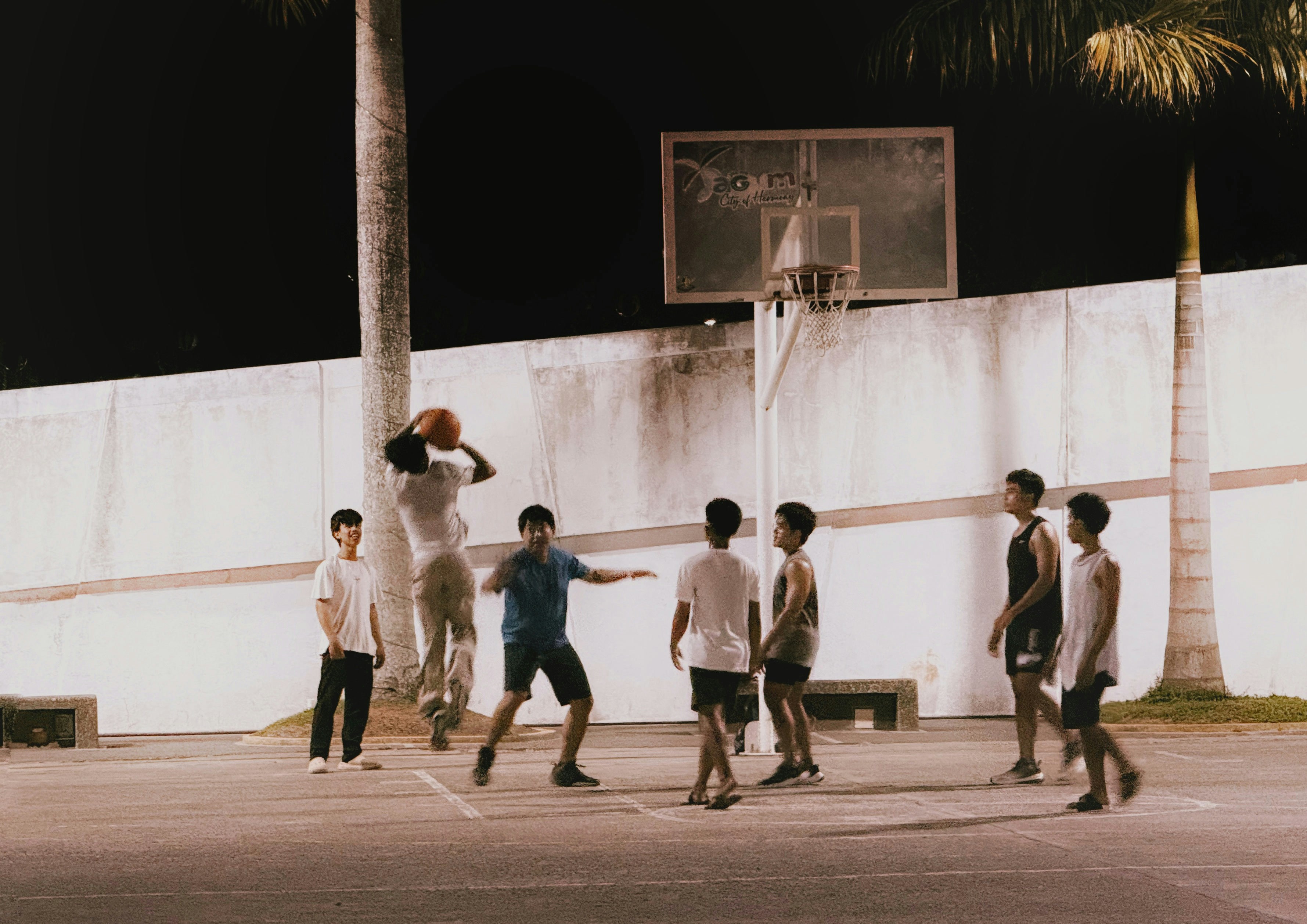 Kinder spielen Basketball auf einem beleuchteten Platz in der Nacht