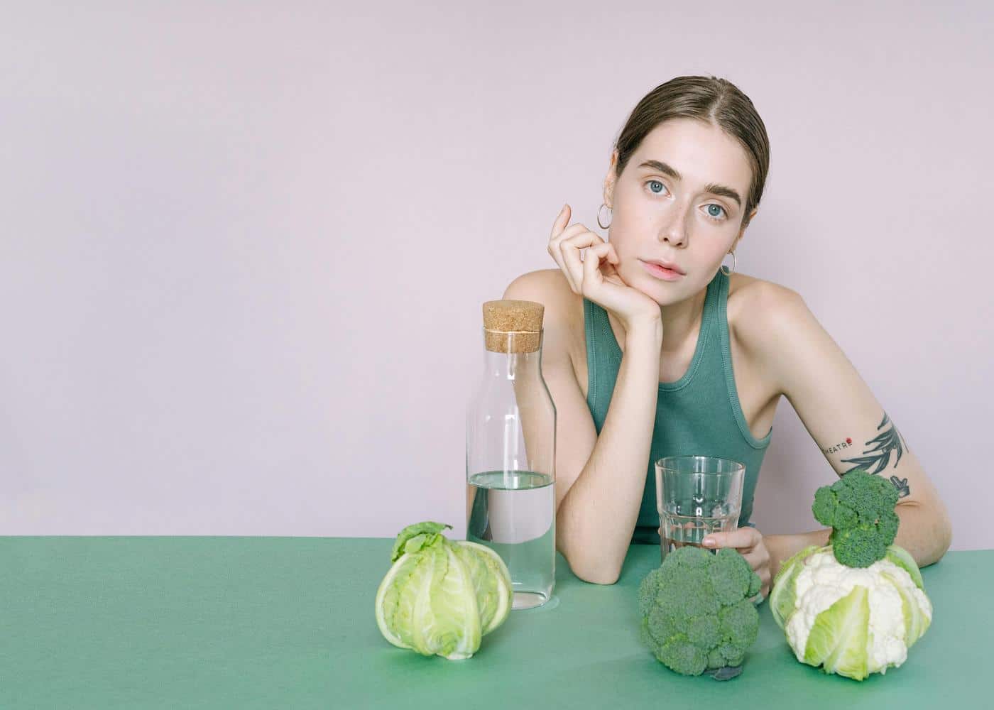 Woman with veggies and water bottle and glass in fron of her