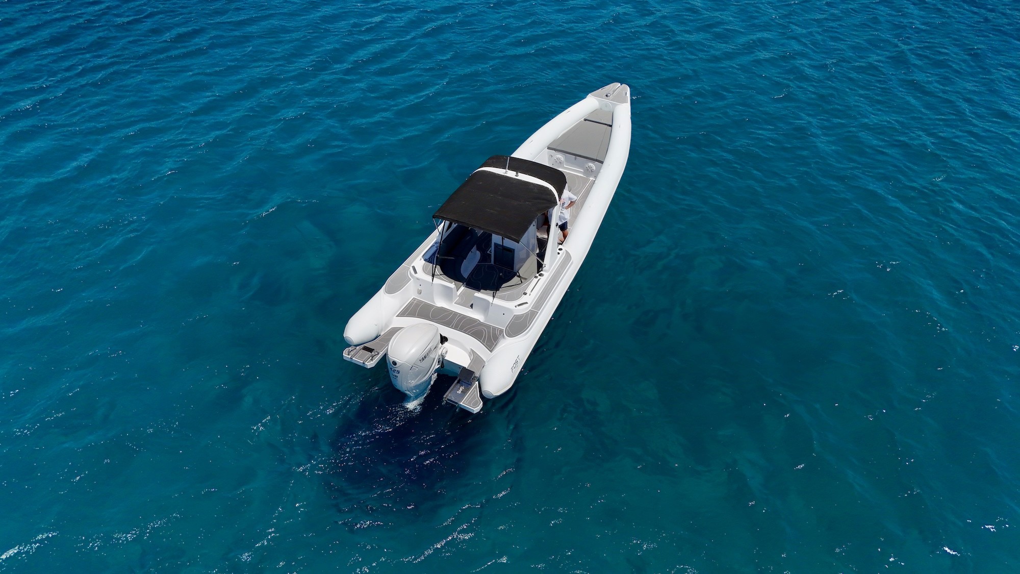 White Fost Matrix 32 catamaran yacht with black sunshade anchored in crystal-clear turquoise waters of the Aegean Sea.