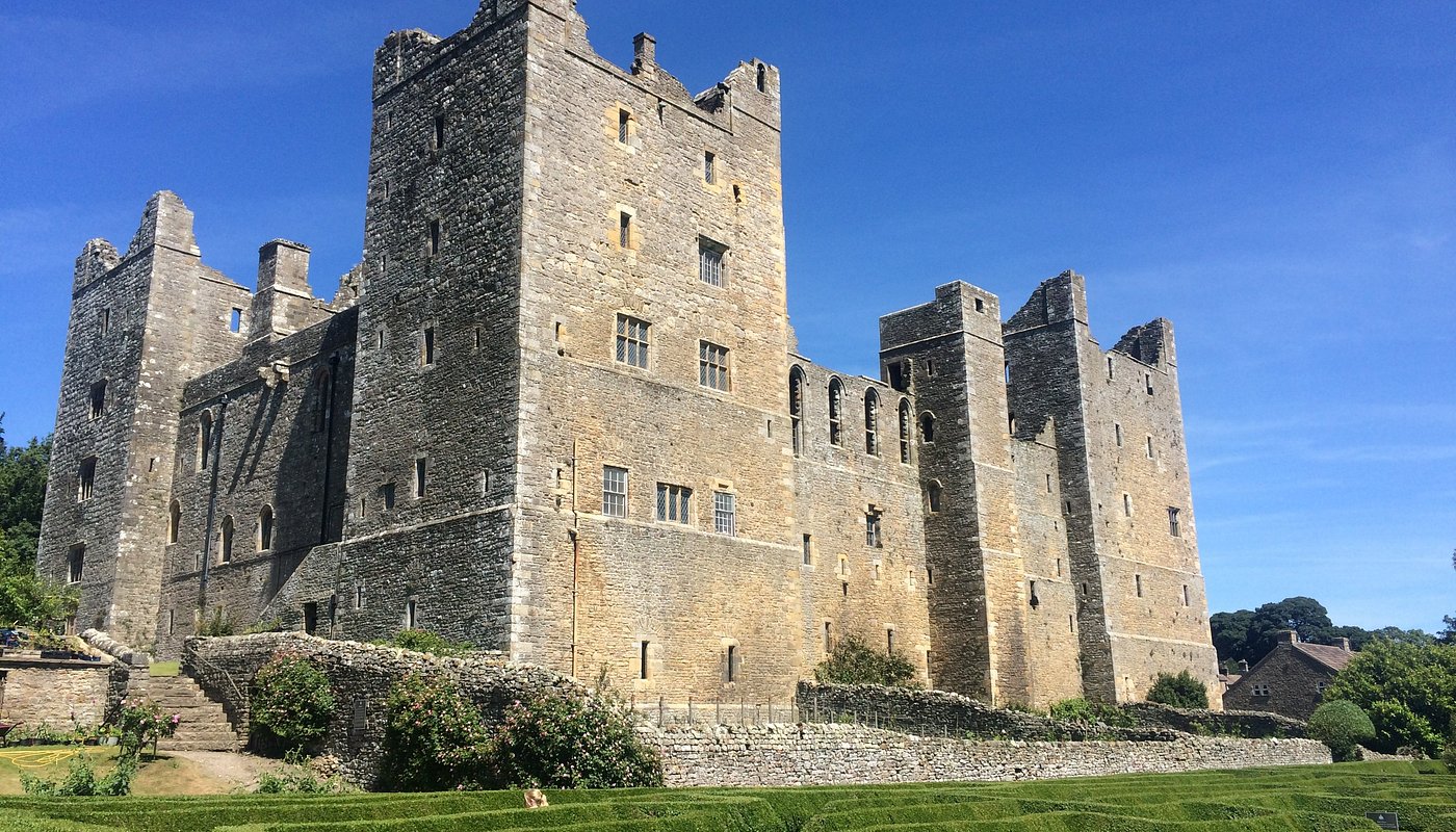 Impressive medieval stone castle with tall defensive towers and historic battlements against bright blue sky background