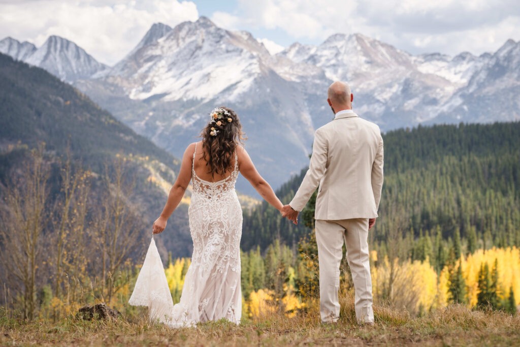 Bride and groom standing together at Maroon Bells, looking out over the mountains in the distance.