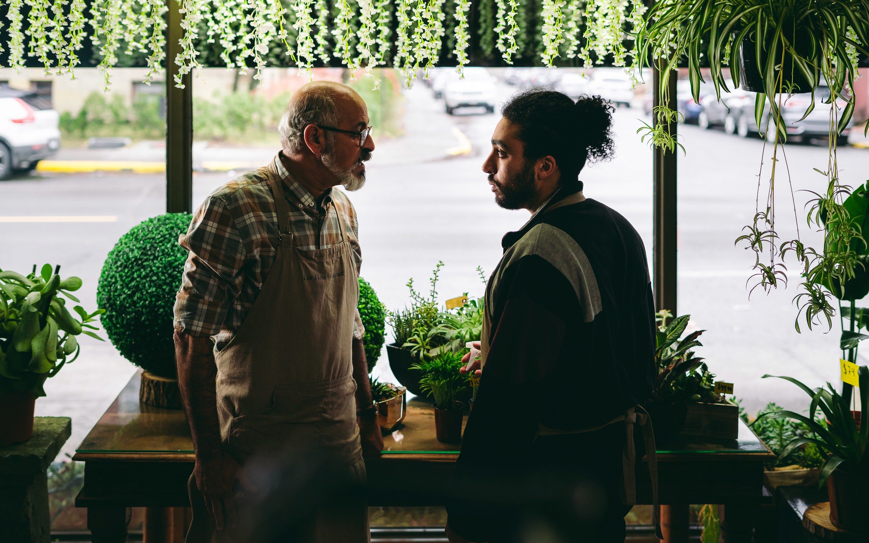 Anas Hassouna et Said Benyoucef en conversation sérieuse à l'intérieur de la boutique. Scène tiré de la série web Les Fleuristes