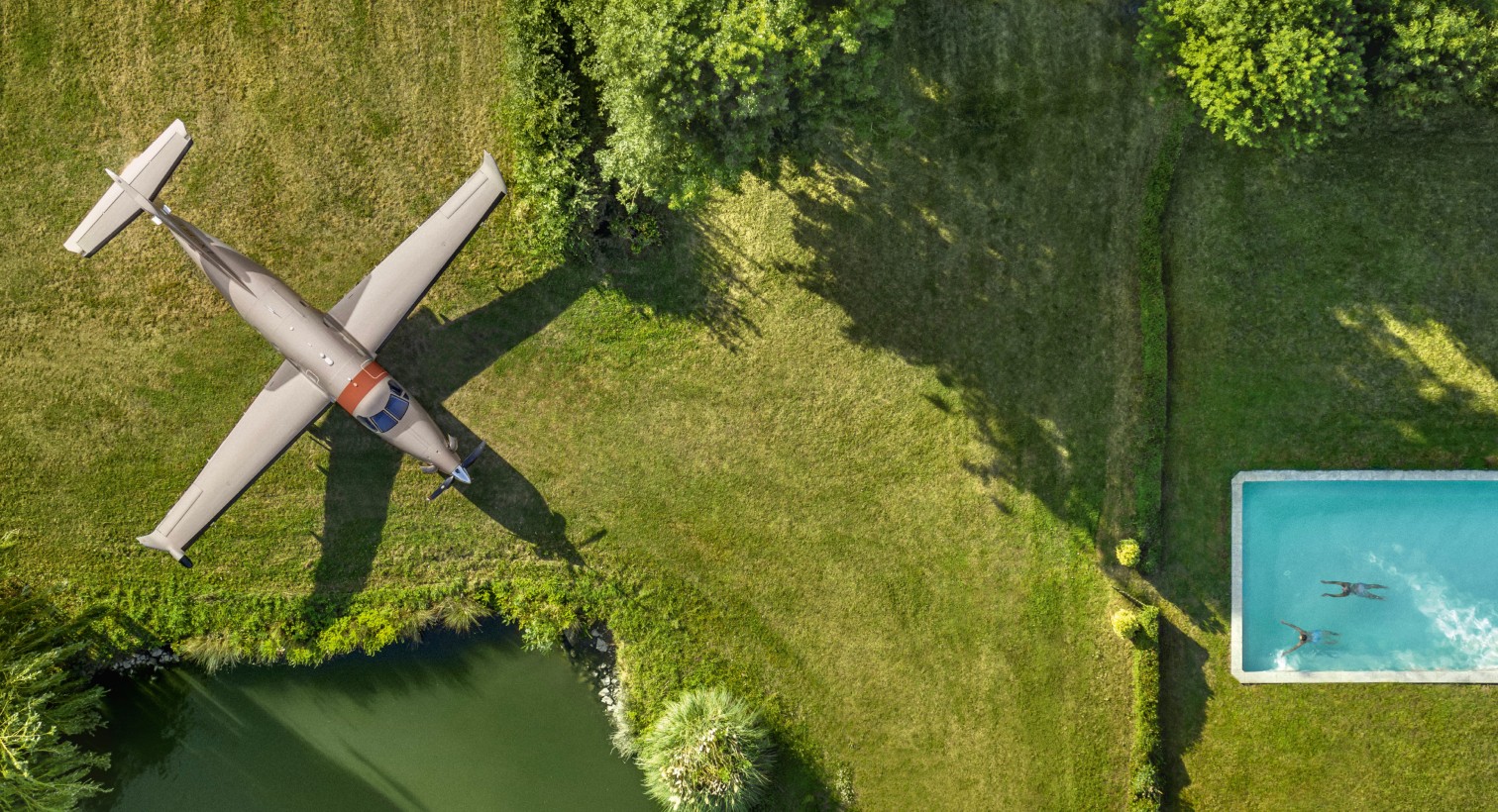 Pilatus PC-12 on grass at private property with swimming pool