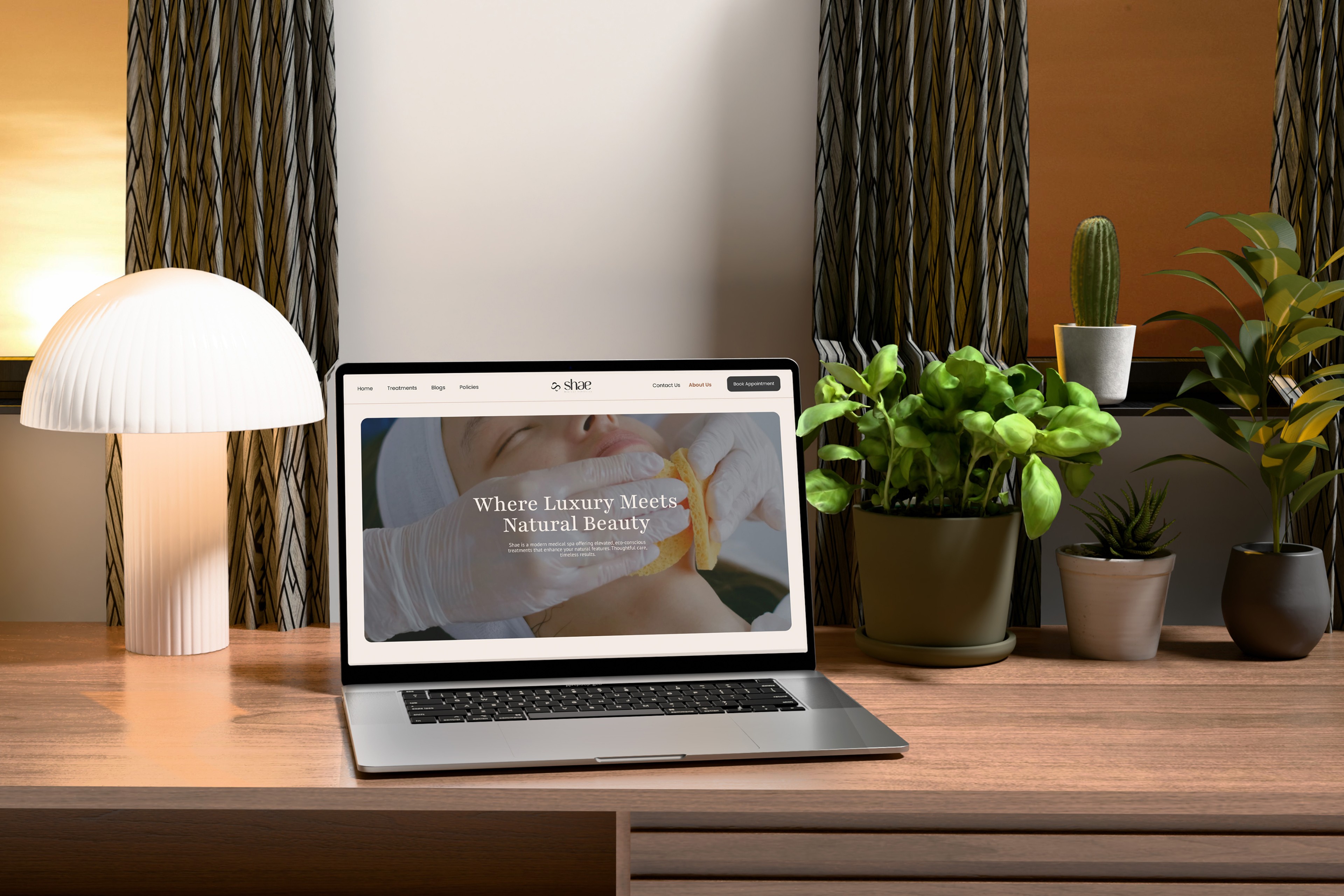 Laptop on a wooden desk displaying the Shae Medical Aesthetics website with the tagline 'Where Luxury Meets Natural Beauty,' featuring an image of a facial treatment, surrounded by indoor plants and a modern lamp, creating a serene and elegant workspace.