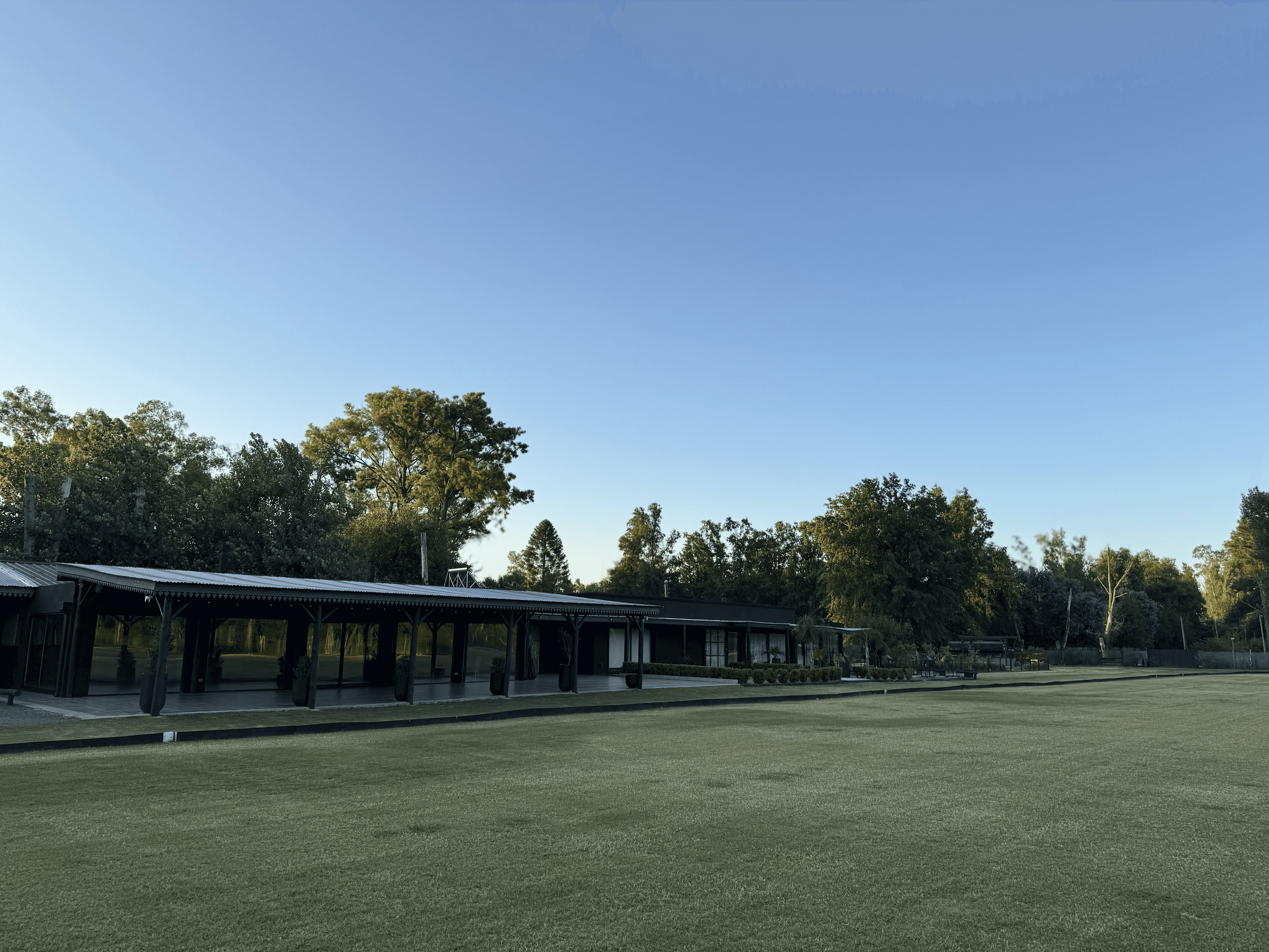 Smiling young woman with long hair standing against a dark green background, holding a finger to her chin.