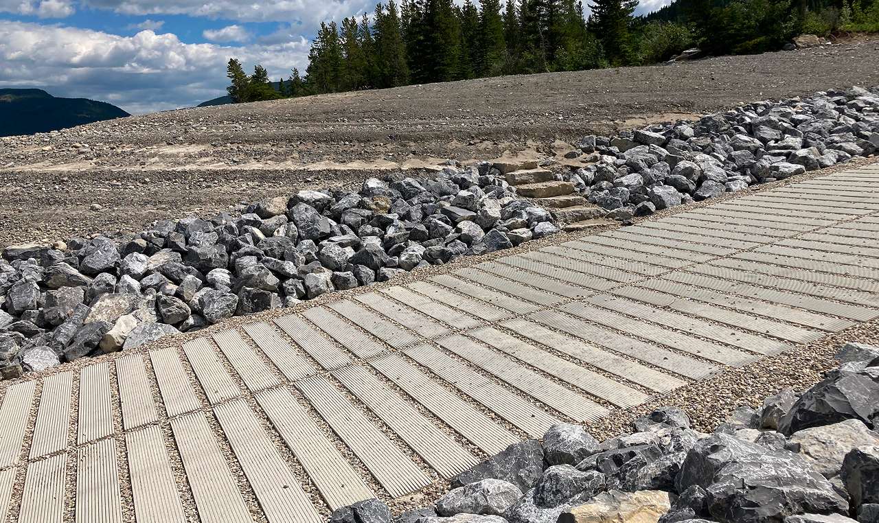 Completed boat launch ramp extending into Barrier Lake with forested Rocky Mountain slopes