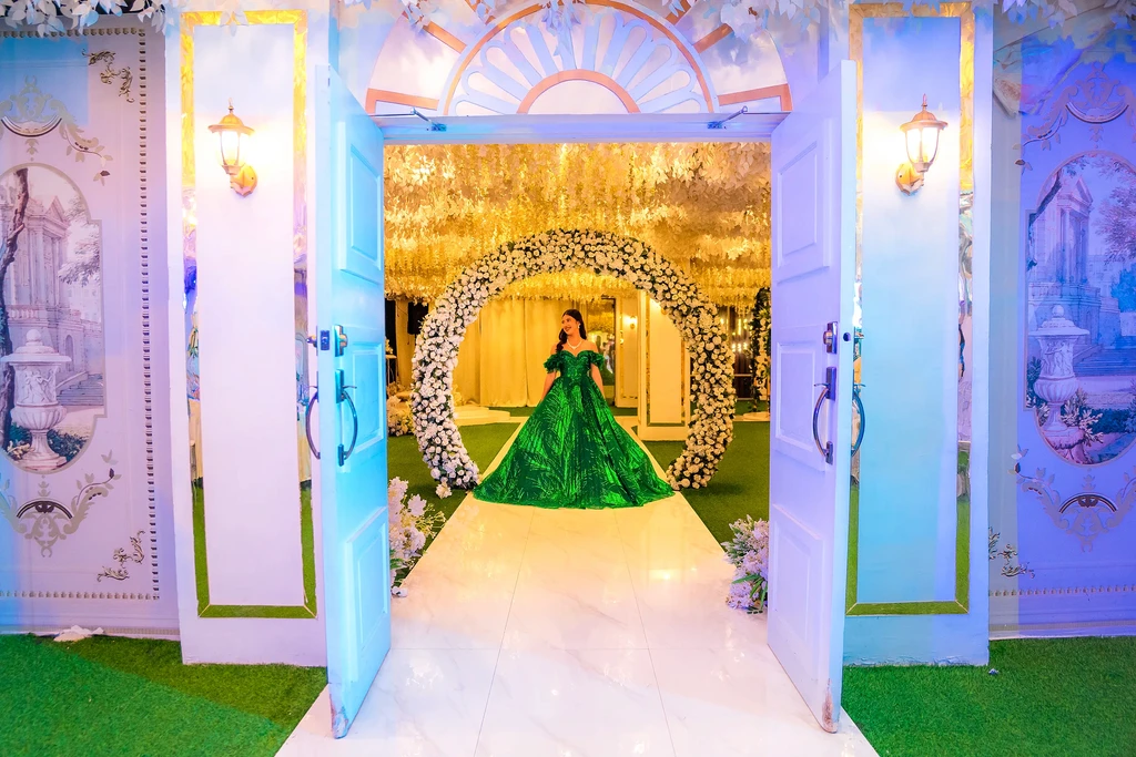Debutante in green entering through the floral arch doorway at Celestia Hall
