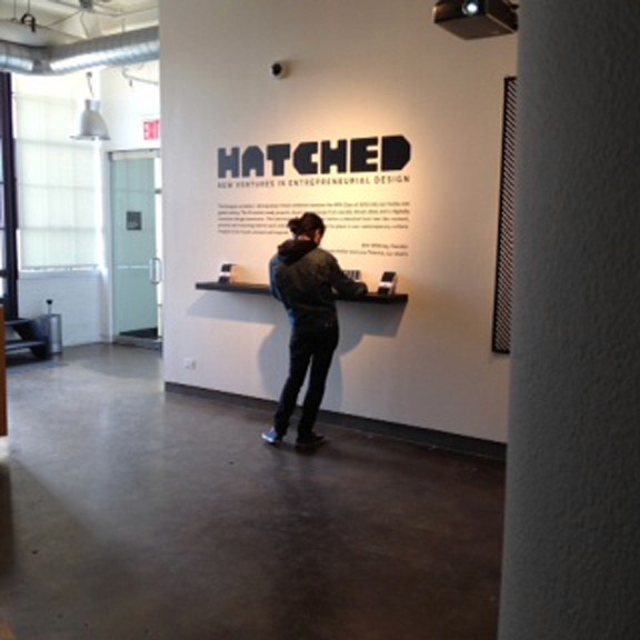 A photo of a person standing near a wall with the text Hatched and some other information on it.