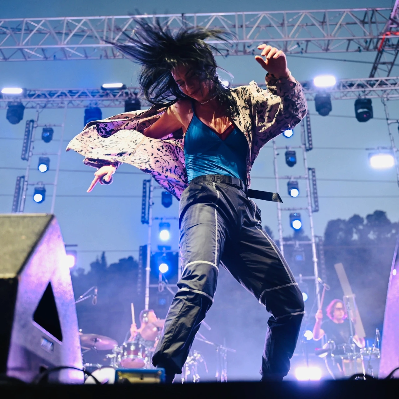 נינט טייב בהופעה חיה, צילום אנרגטי של רגע שיא על הבמה עם שיער מתנפנף ותאורת מופע מקצועית. צילום הופעות על ידי Shiriz הצלמת שירי עציץ