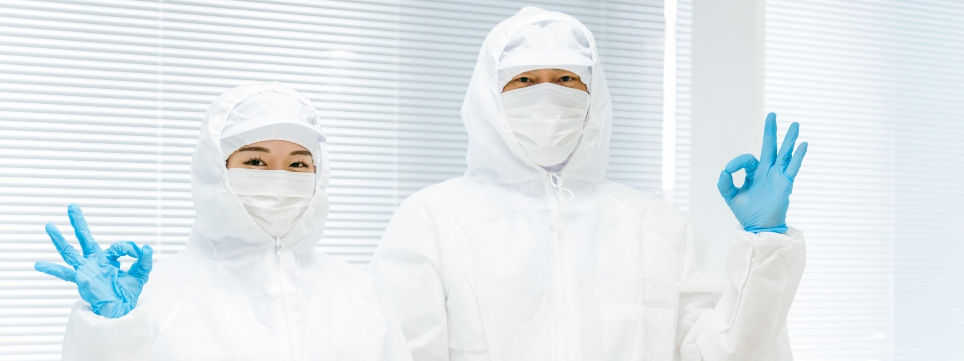 クリーンルームでOKサインをする作業員二人の画像