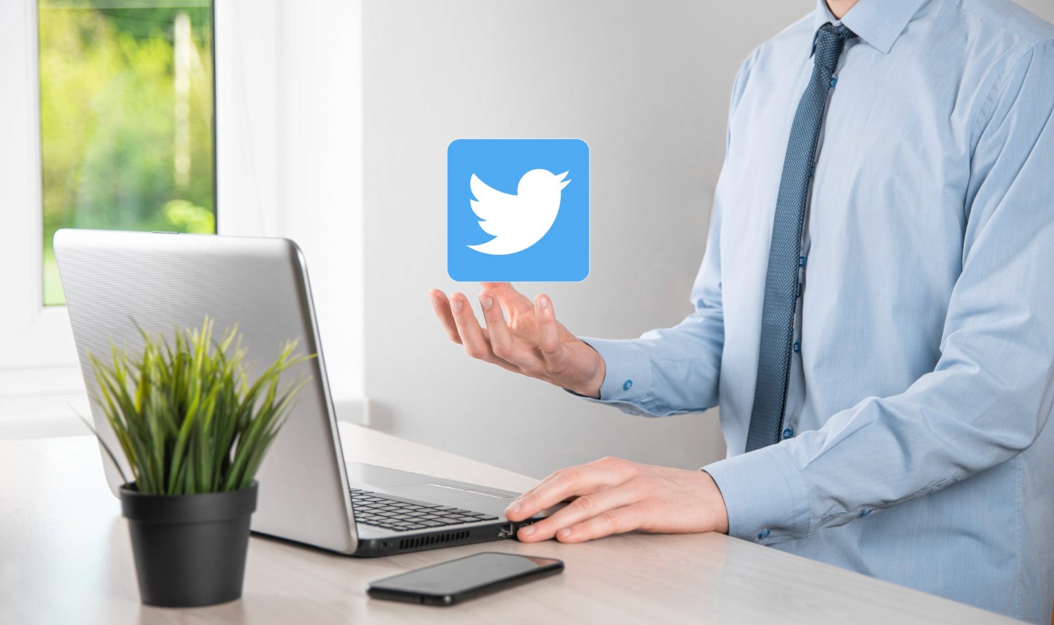  A man in a blue shirt holds a laptop displaying the Twitter icon, symbolizing social media engagement.