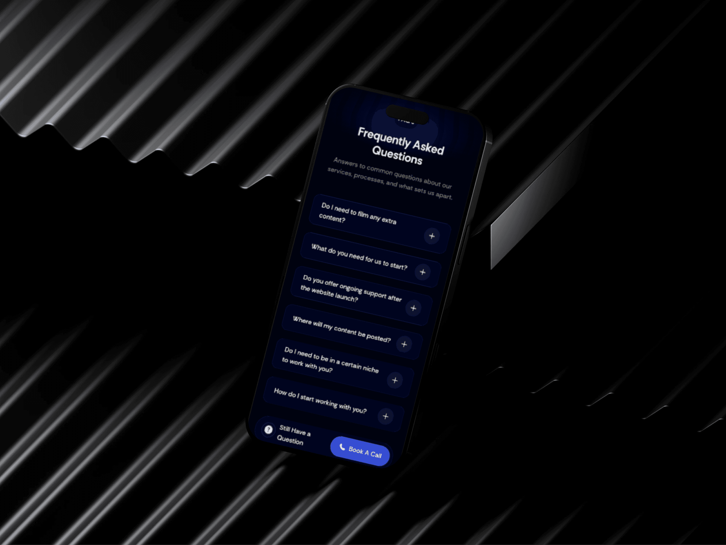 A smartphone displaying a "Frequently Asked Questions" screen is placed on a surface with a zigzag pattern, featuring questions about extra equipment, website support, file sizes, network connection, and logins.