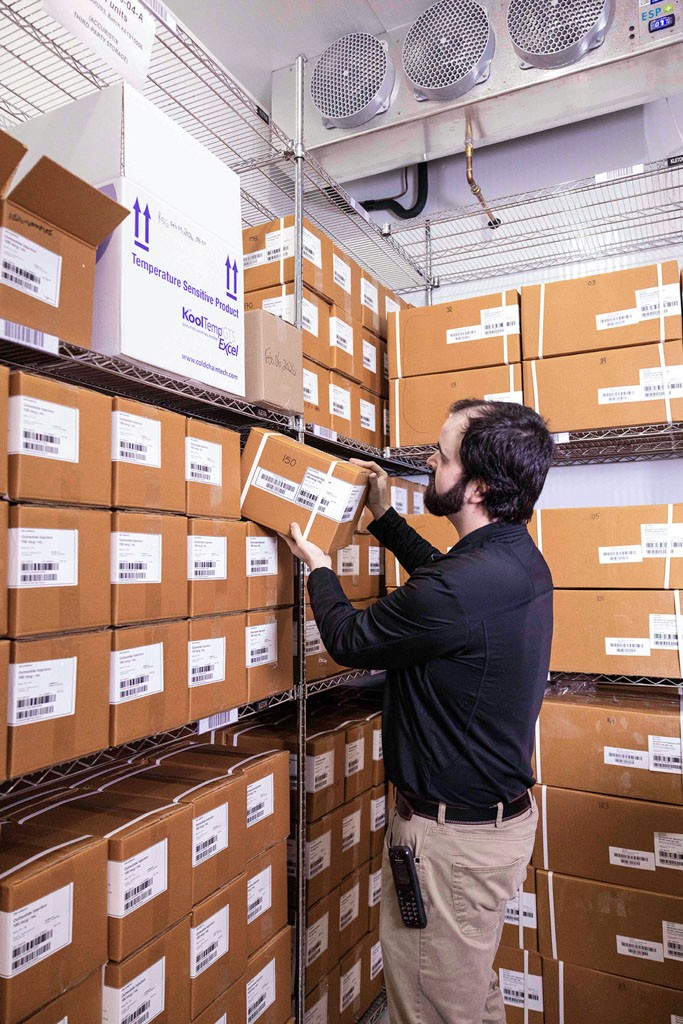 A SteriMax team member organizing pharmaceutical products in a storage warehouse.
