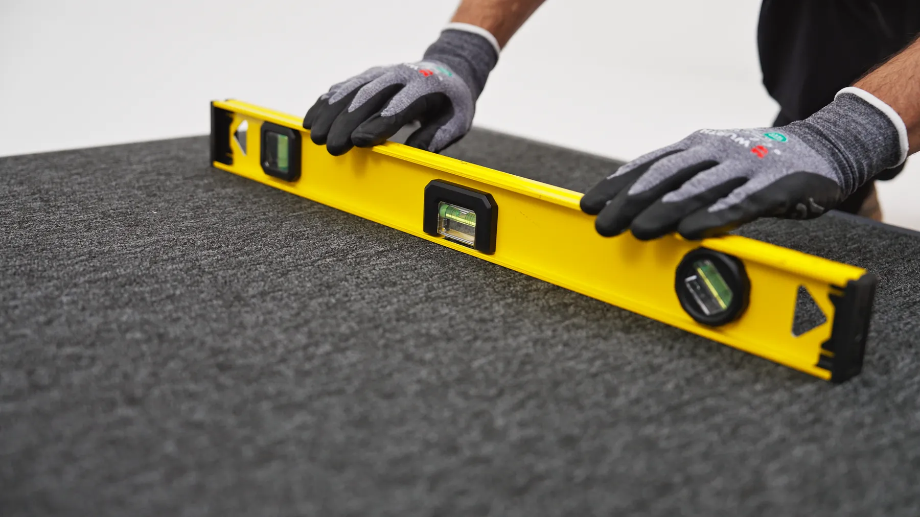 Gloved hands checking a pod's base panel is level with a spirit level