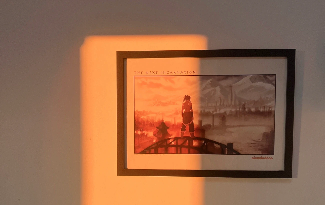 A framed 'The Next Incarnation' poster of Korra overlooking Republic City, caught in a warm sunrise light.