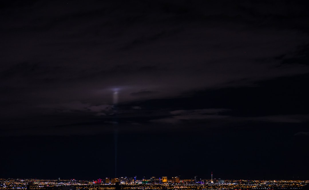 City lights stretched across the horizon beneath a dark, cloudy night sky.