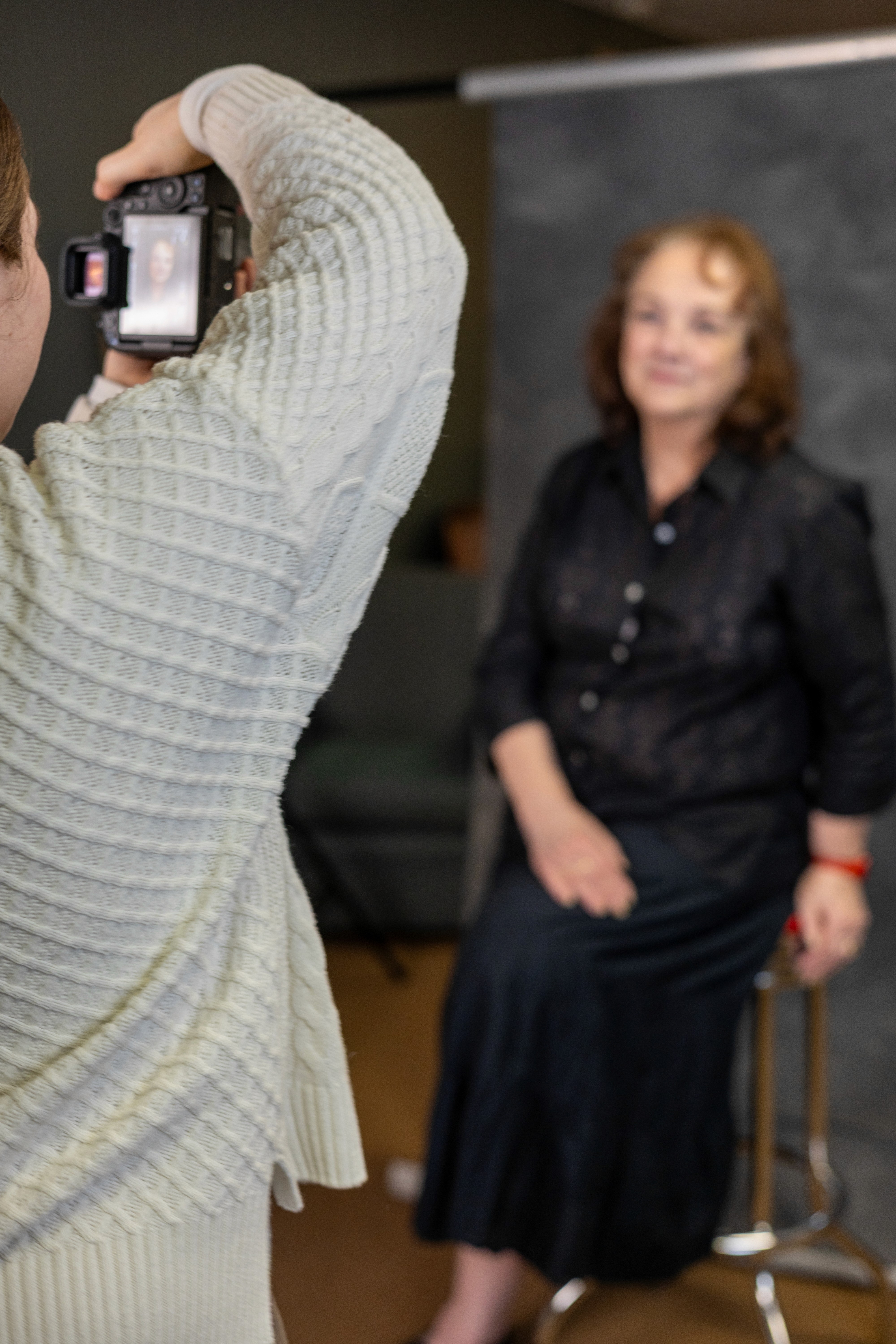 Photo of a female photographer taking a photo of an actor against a canvas backdrop