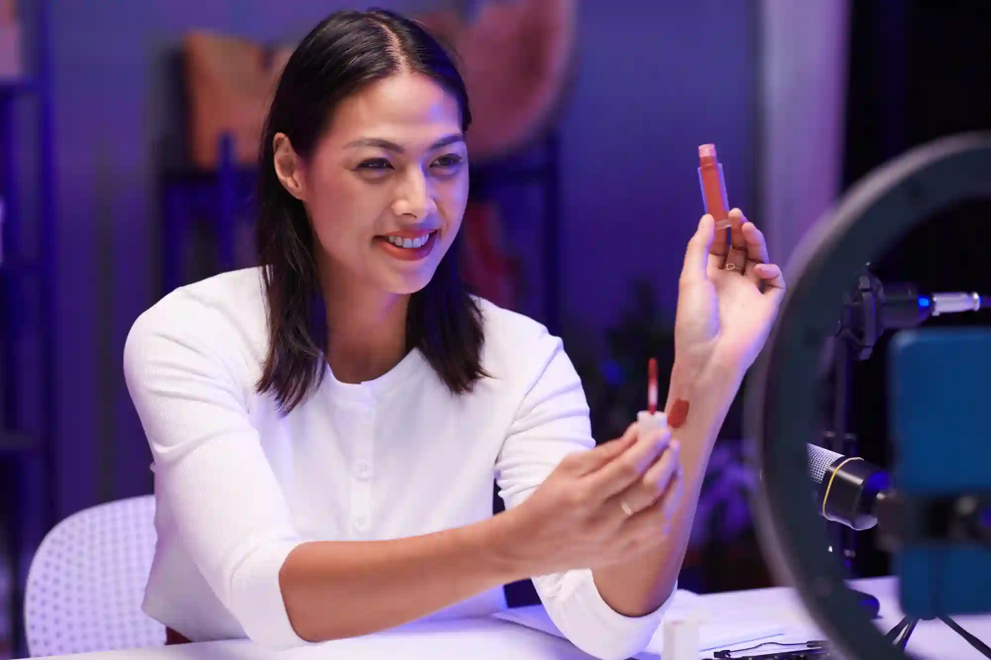 A beauty influencer swatches makeup on her arm for a video.