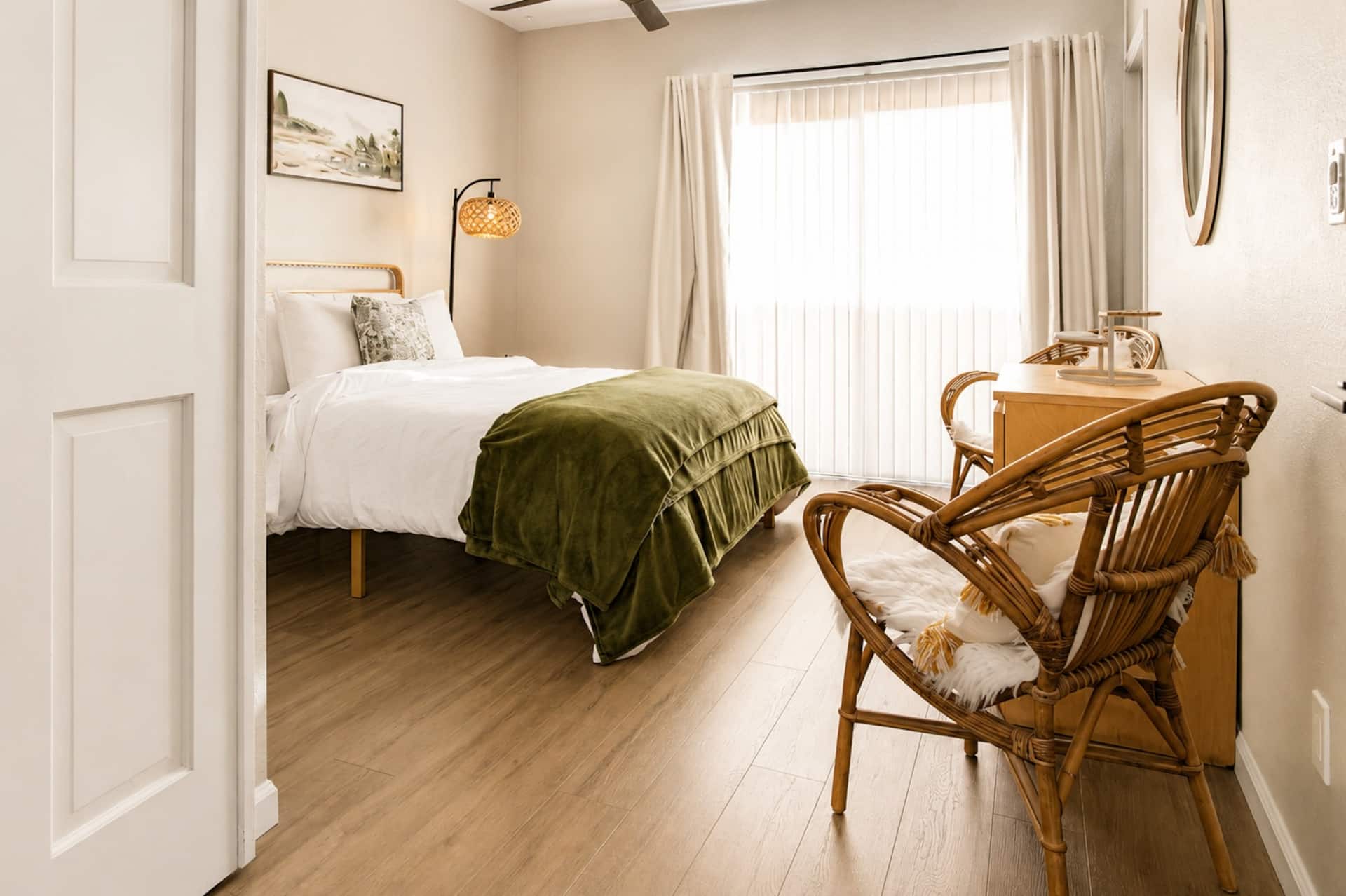 Bright queen bedroom with boho rattan chair and natural light — sleeps 2 comfortably with a warm, relaxed vibe. Great for couples or travel companions sharing the trip.